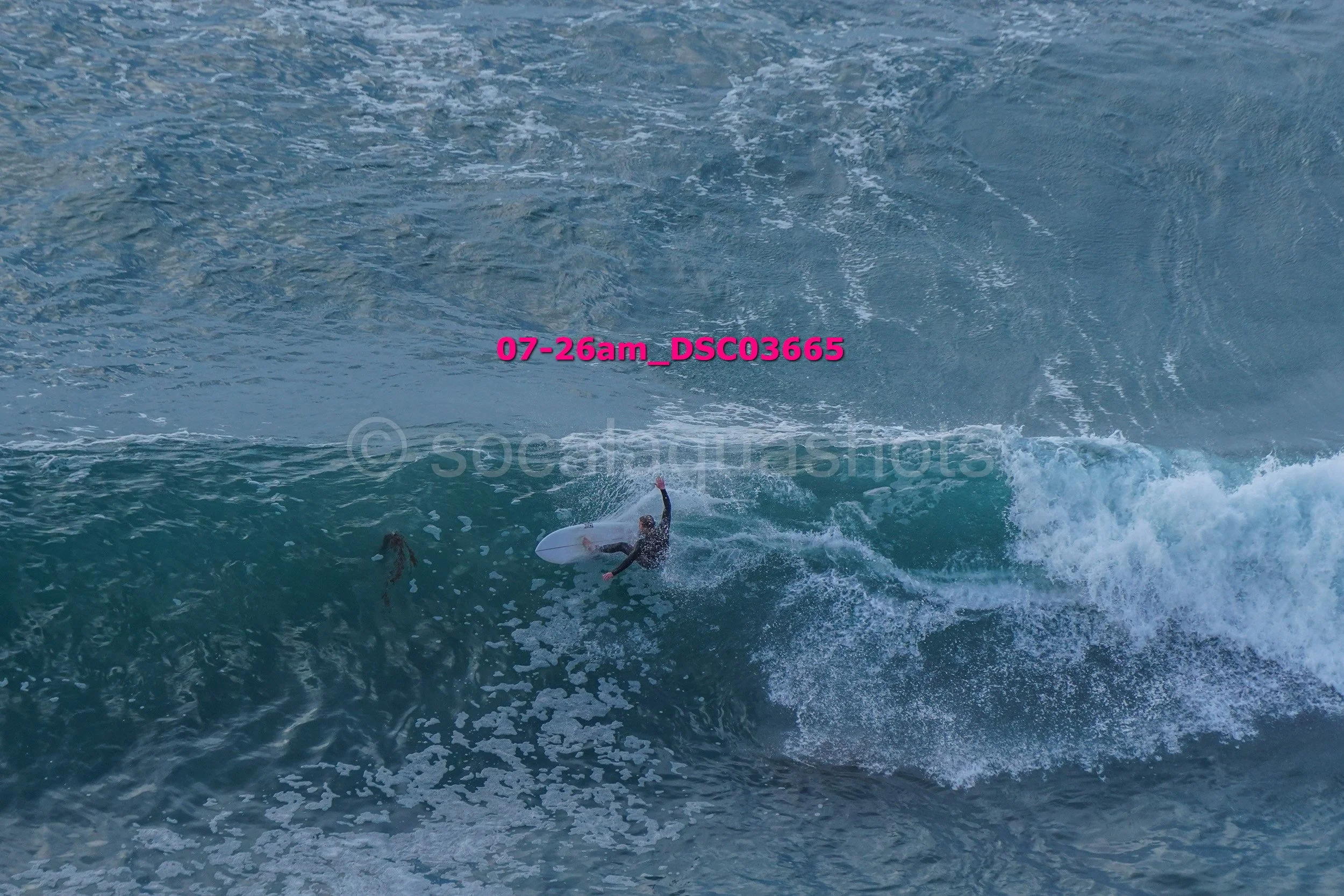 A person in a wetsuit surfing on a large wave in the ocean, with a splash of water around them.