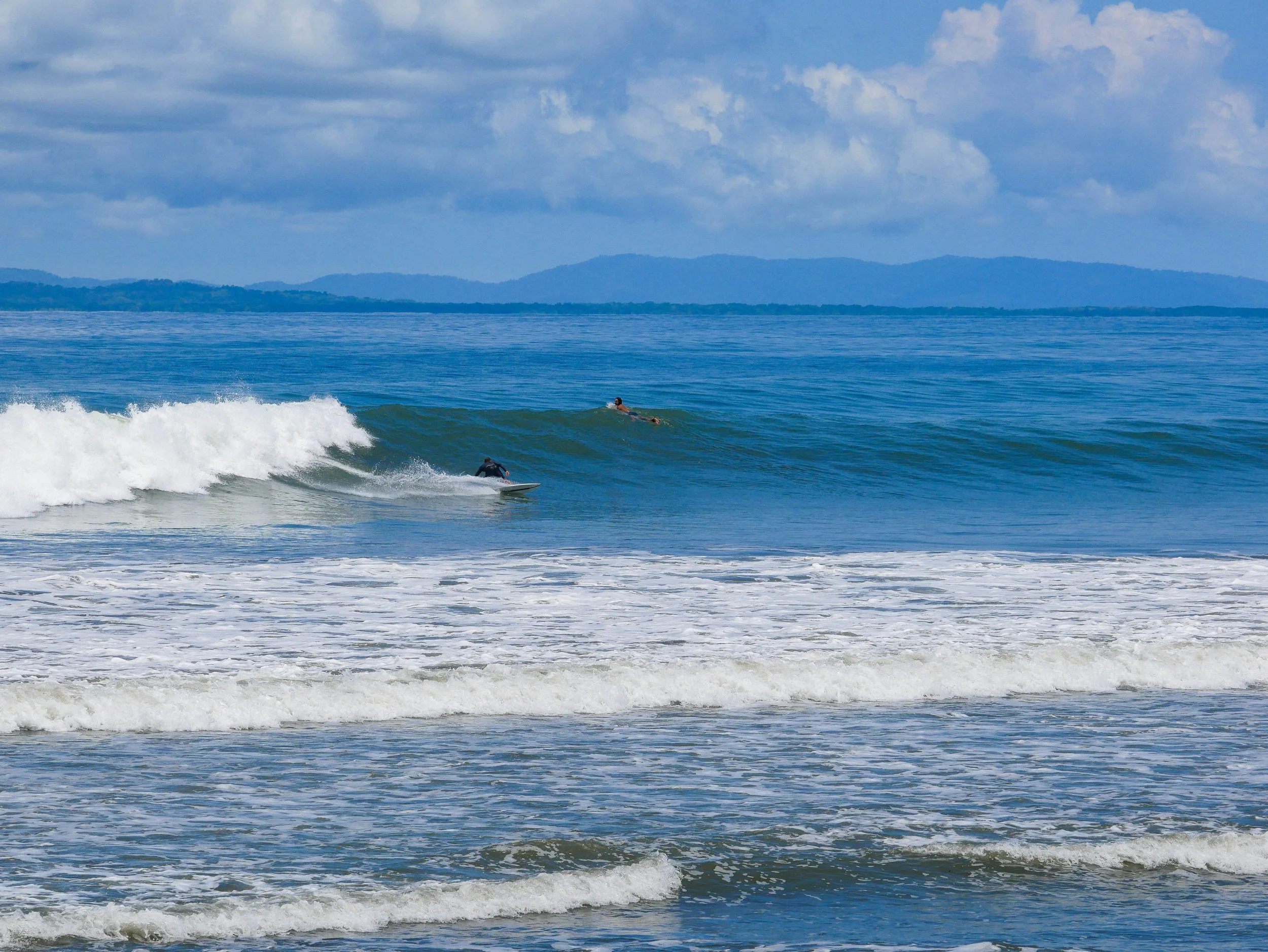 Ocean waves with surfers riding and paddling out