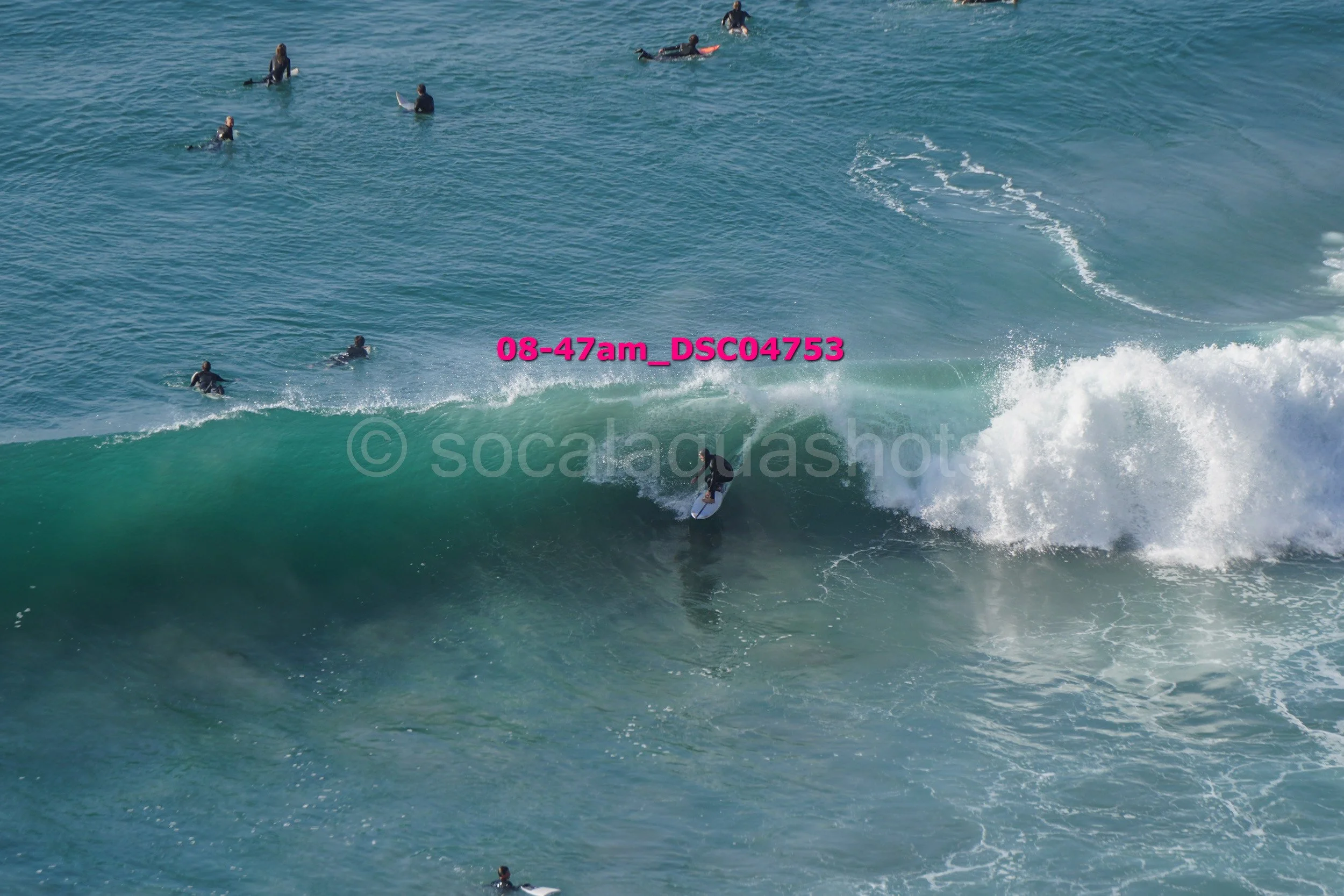 Surfer riding a wave with several surfers in the background in the ocean.
