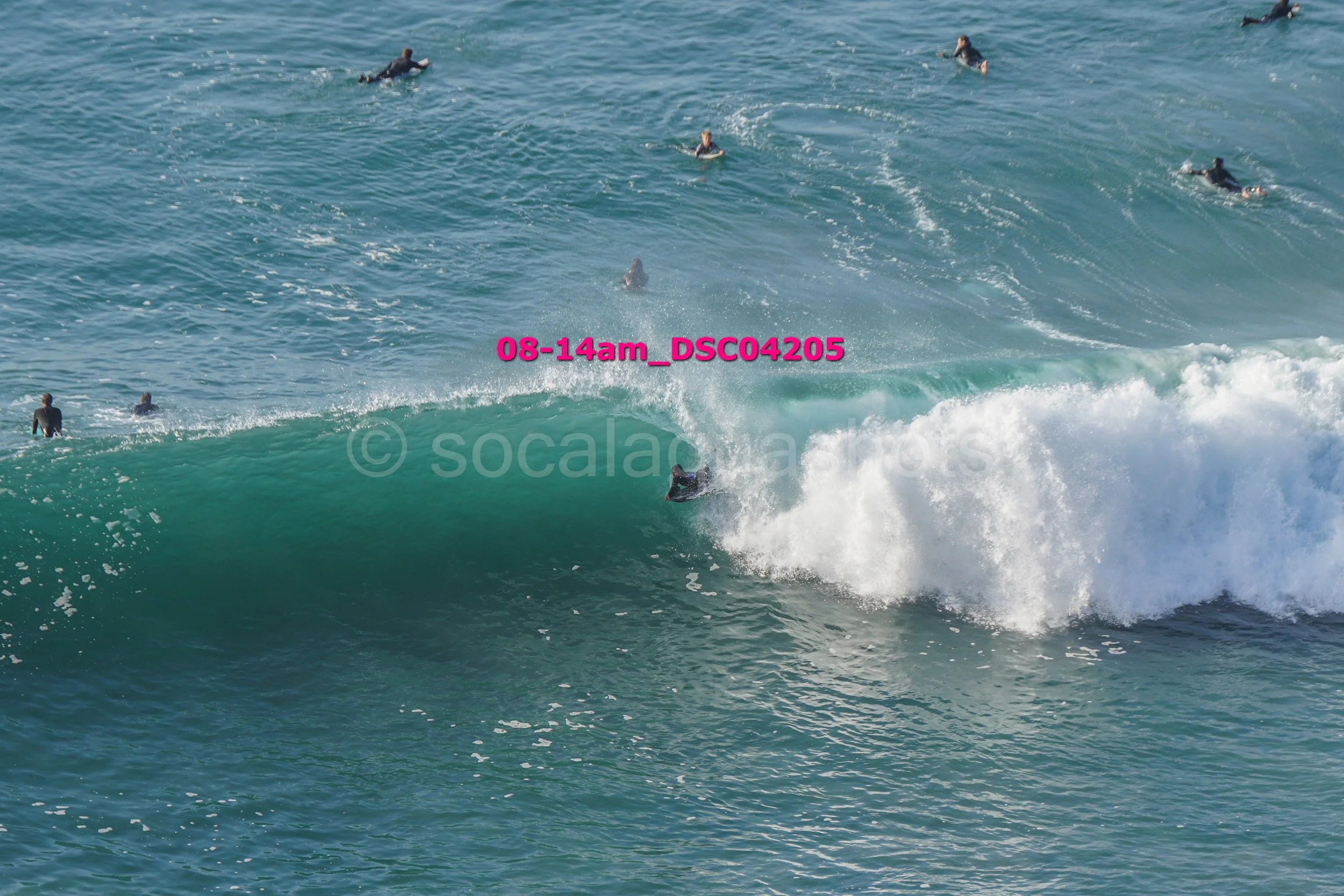 Surfers waiting for waves in the ocean, with one surfer riding a wave.