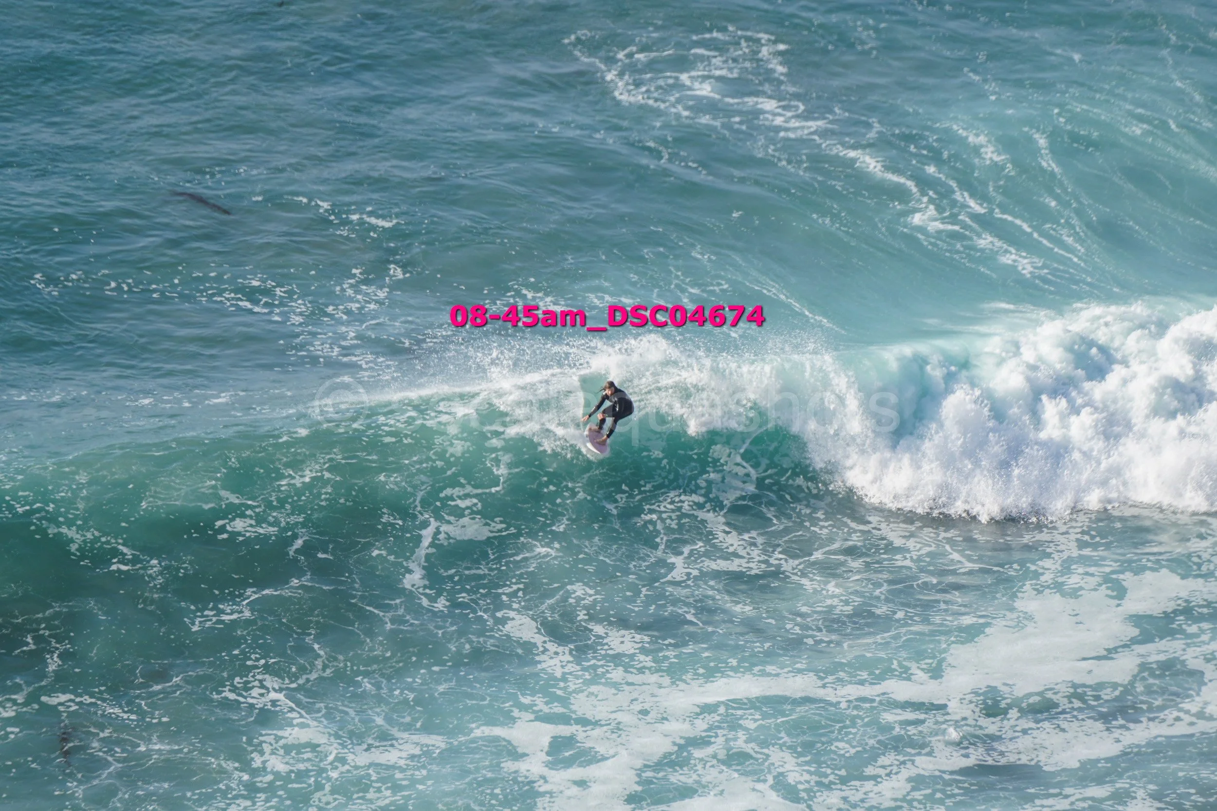A person surfing on a wave in the ocean, with foam and spray around them.