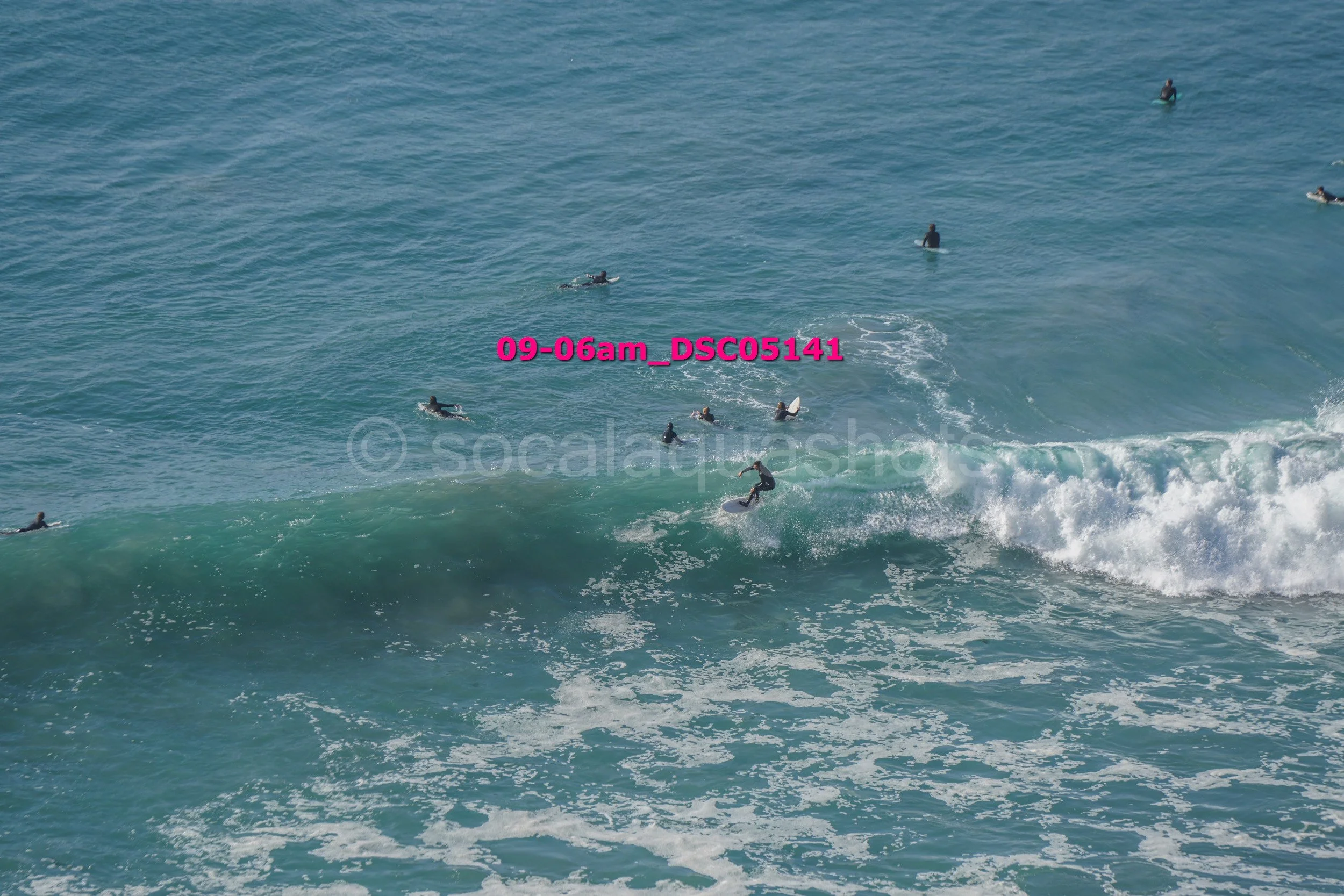 Surfers riding waves and swimming in the ocean.