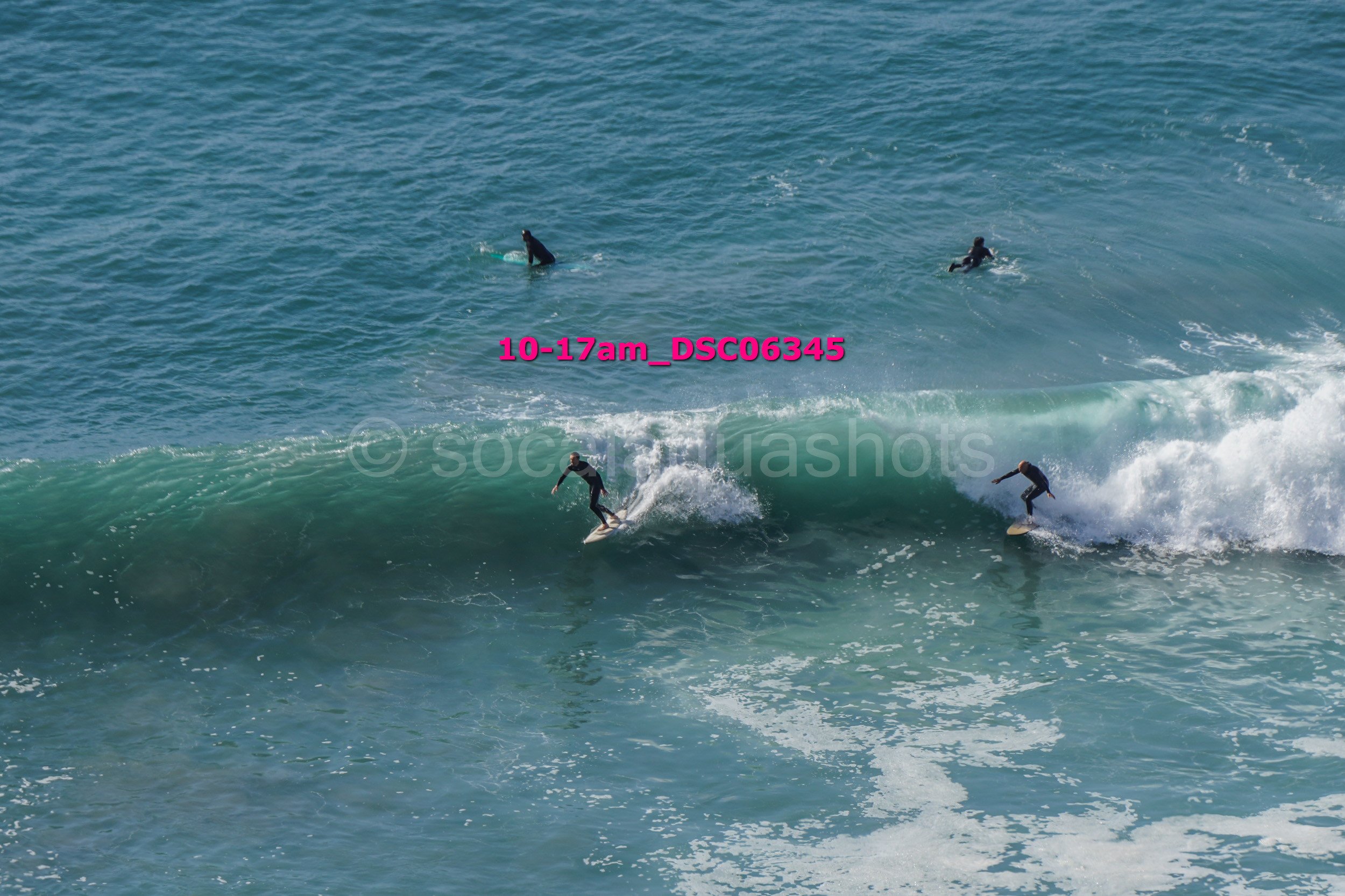 Multiple surfers in wetsuits surfing and riding ocean waves in the sea.