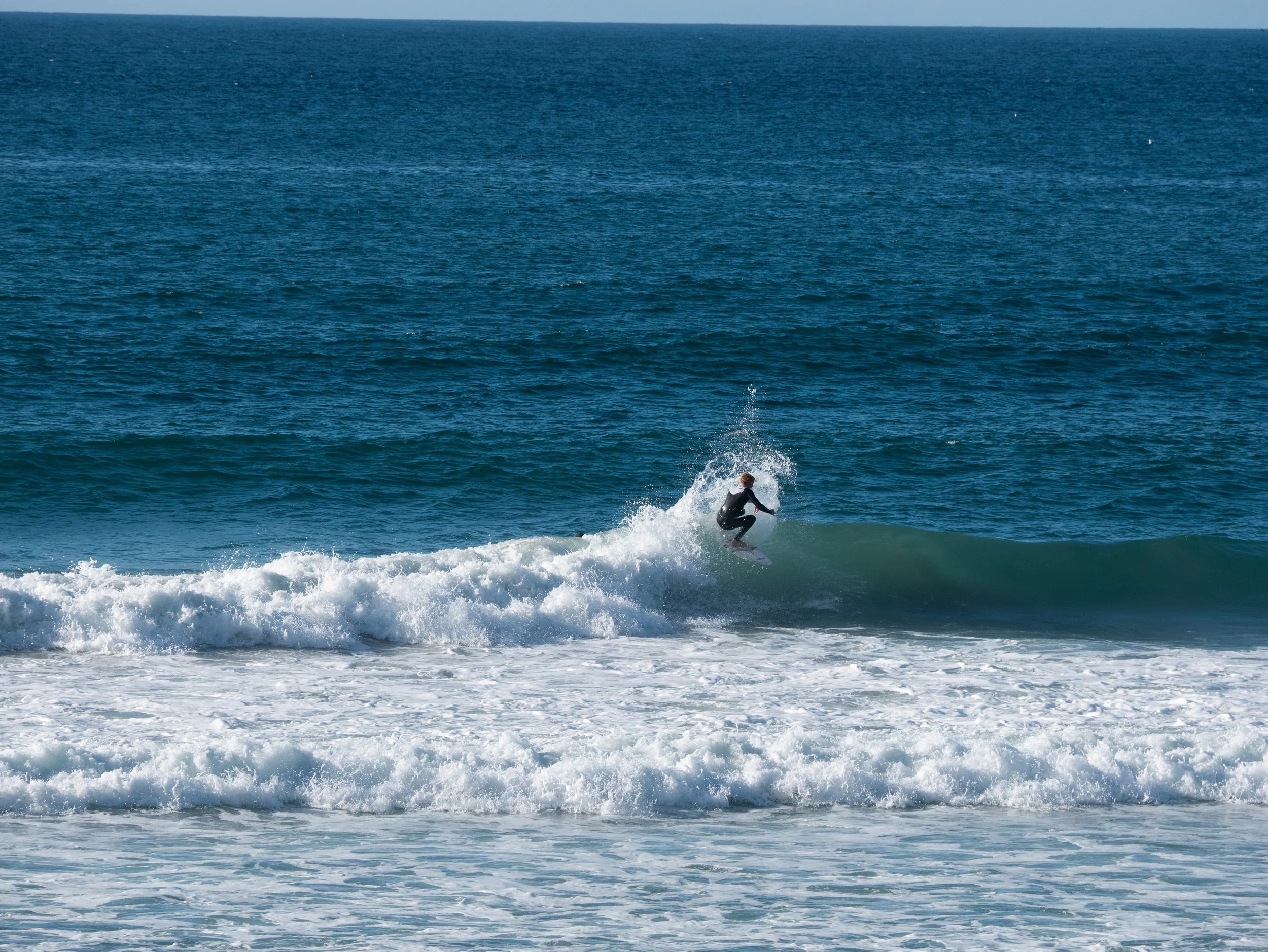 A person surfing on a small wave in the ocean.