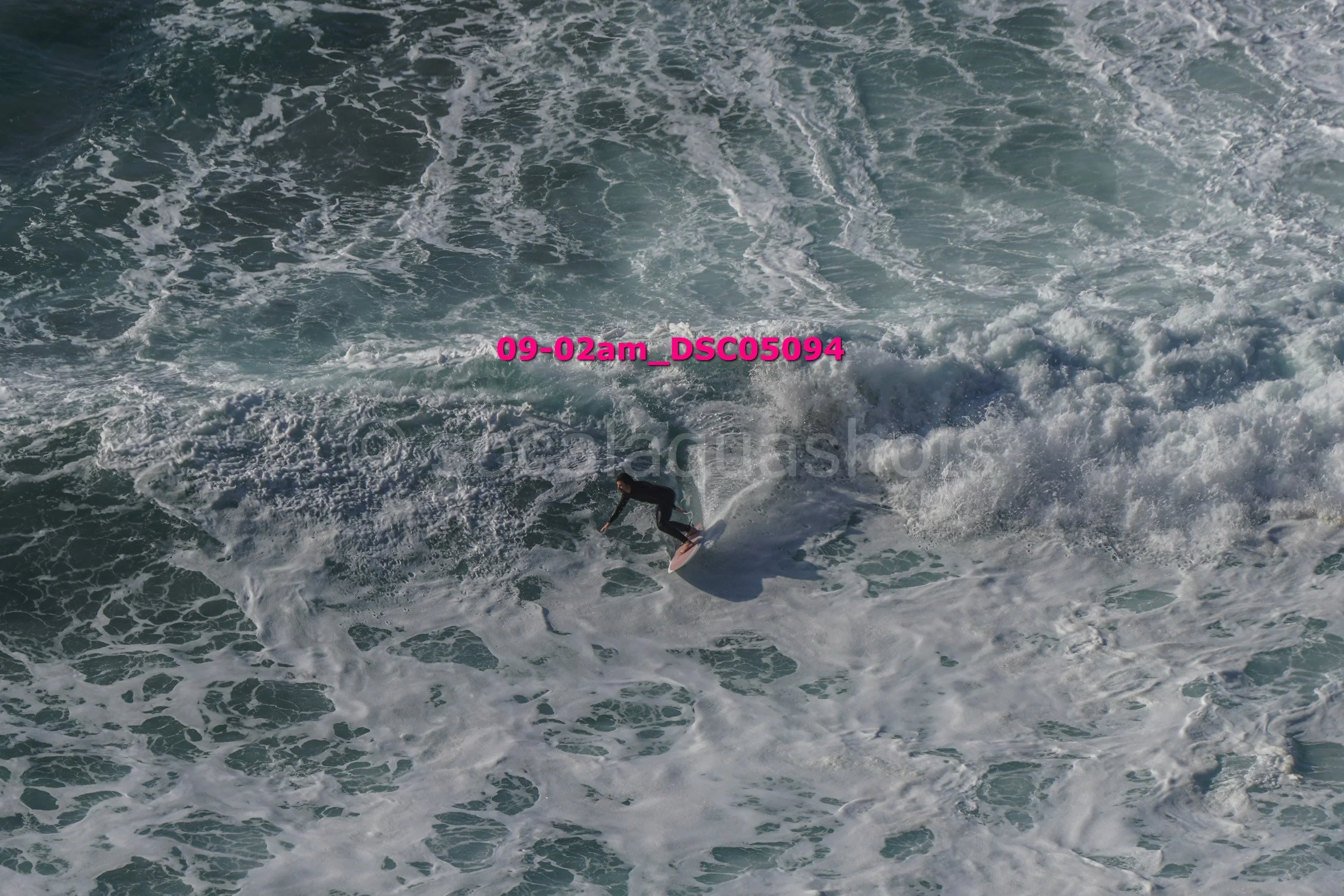 A surfer riding a wave in the ocean during daylight, with white foam and swirling water around him.