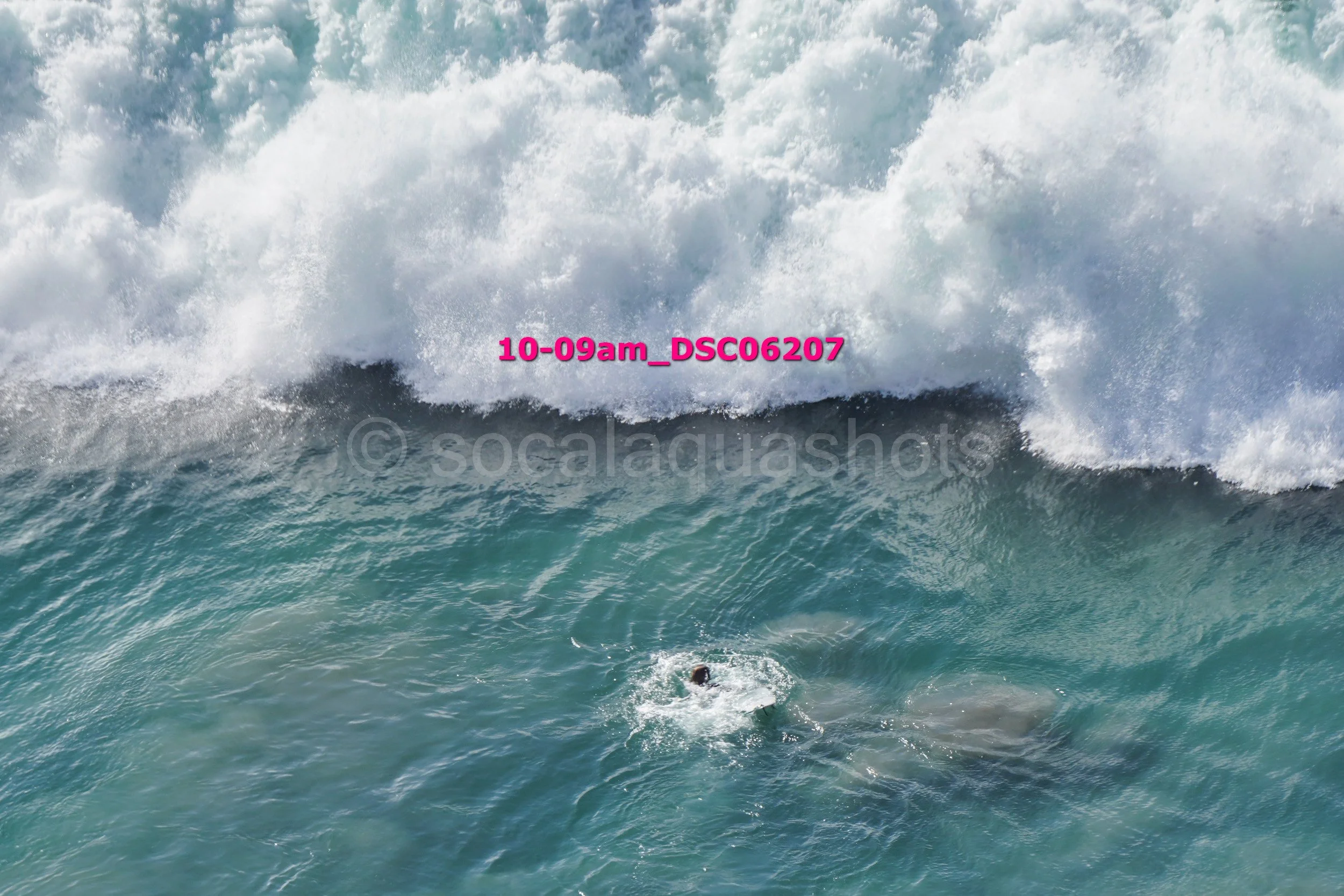 A person surfing in the ocean with large waves crashing behind them.
