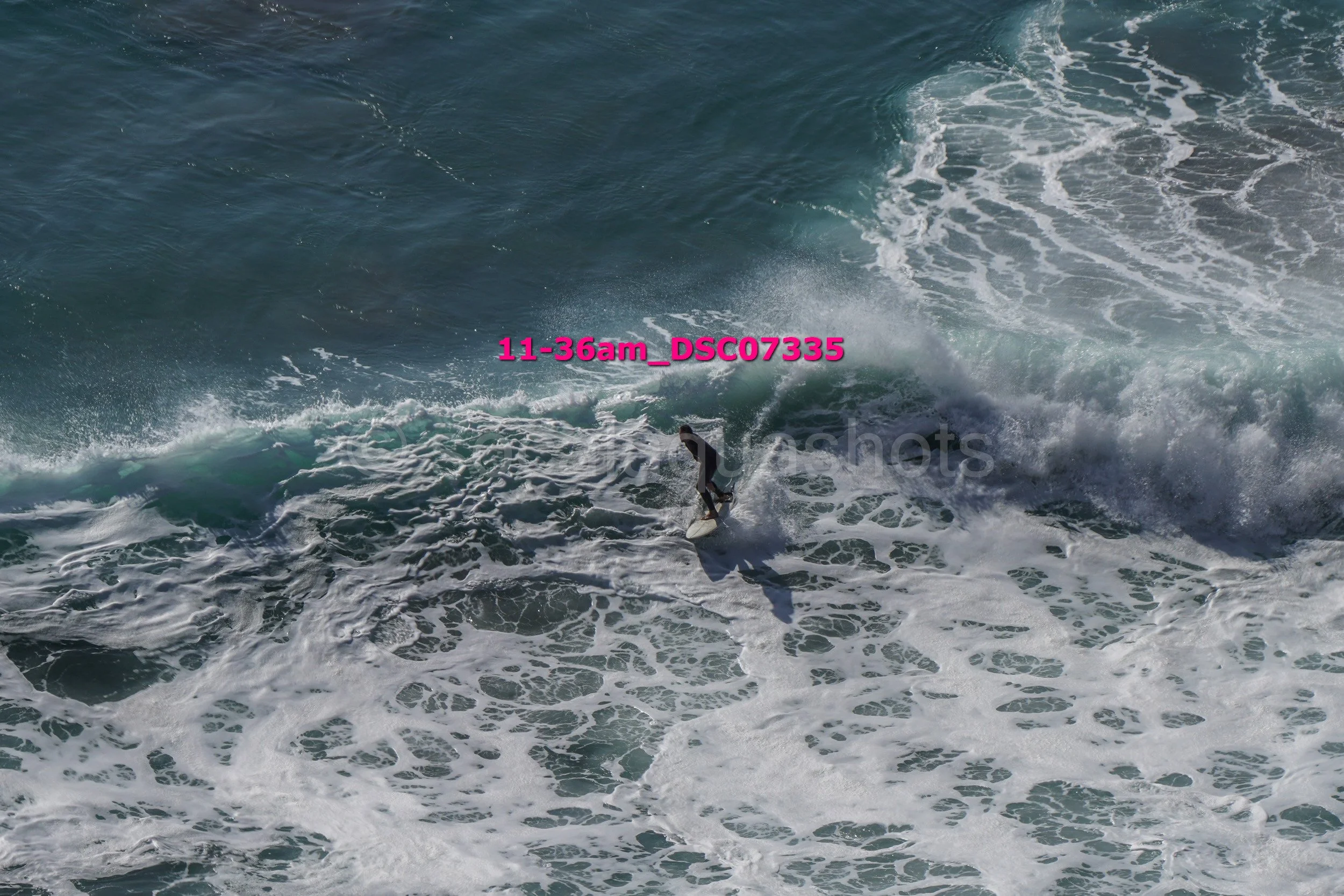 A person surfing on a wave in the ocean, with splashing water around.