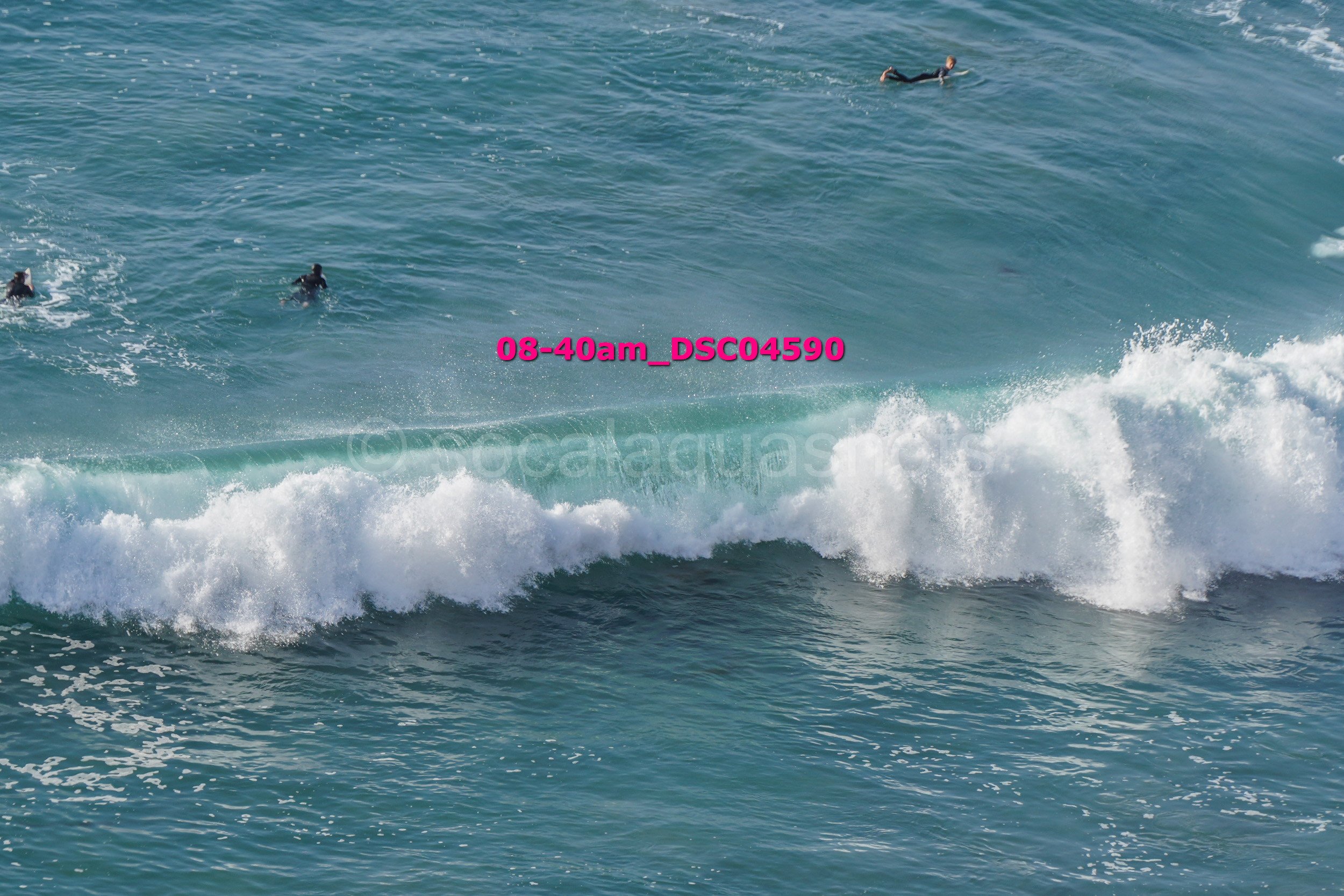 Person surfing on a wave in the ocean with several other surfers nearby.