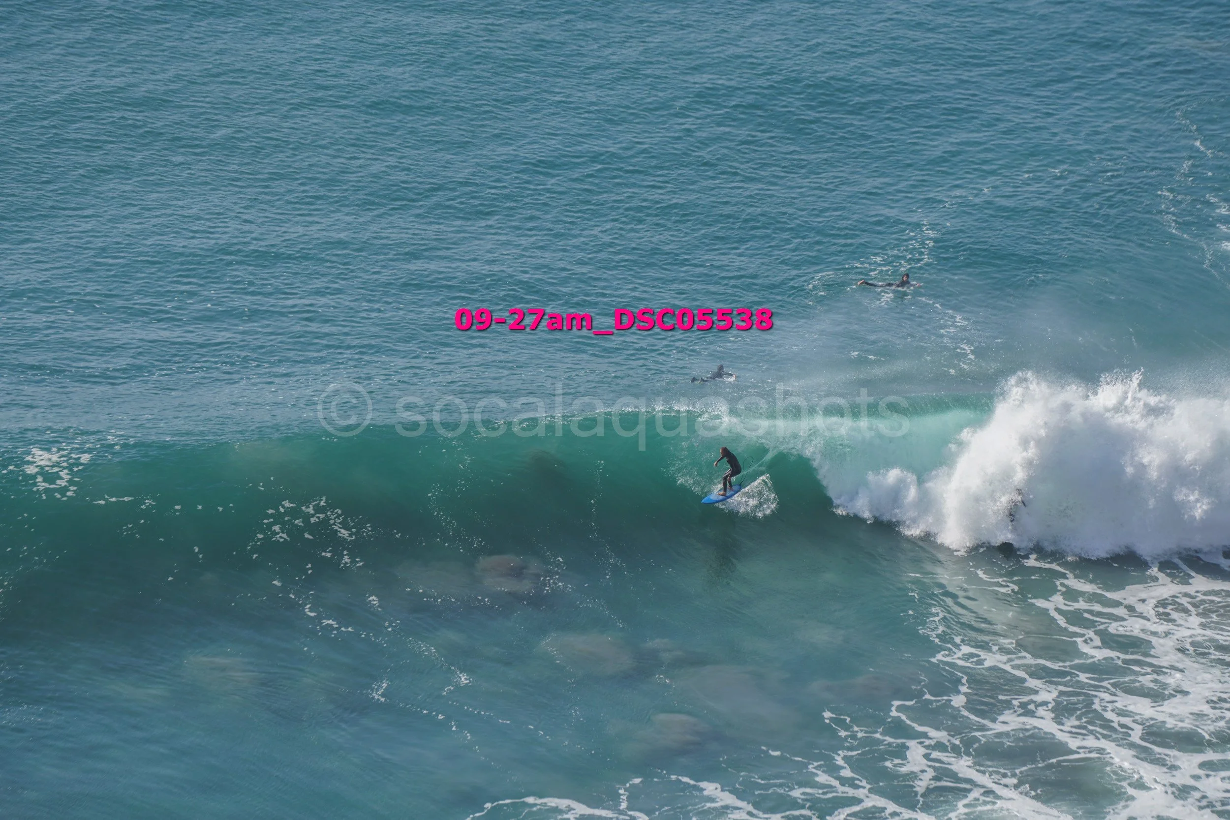 Surfer riding a wave in the ocean with other surfers in the background