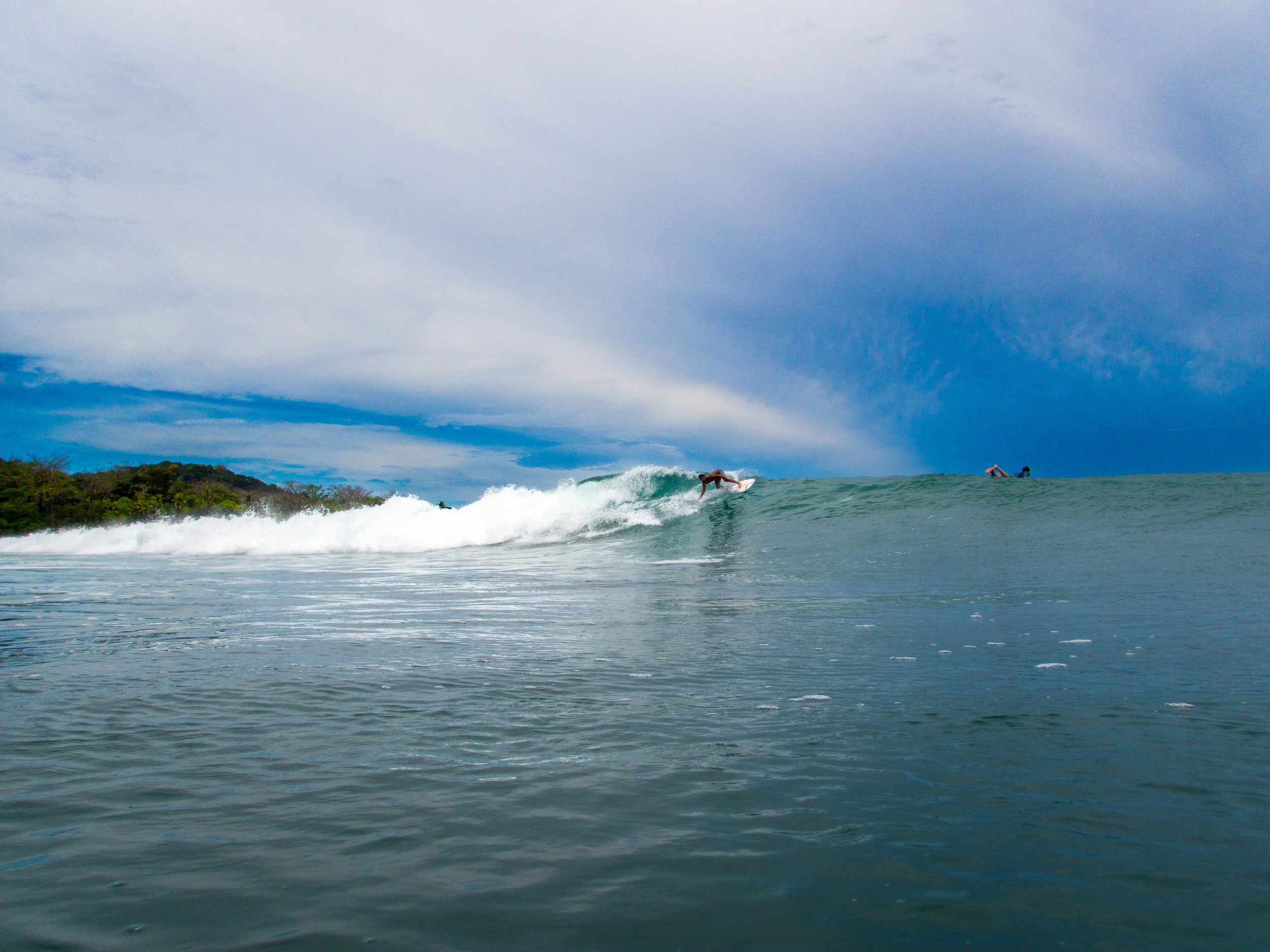 Surfer riding a wave in the ocean with cloudy sky background