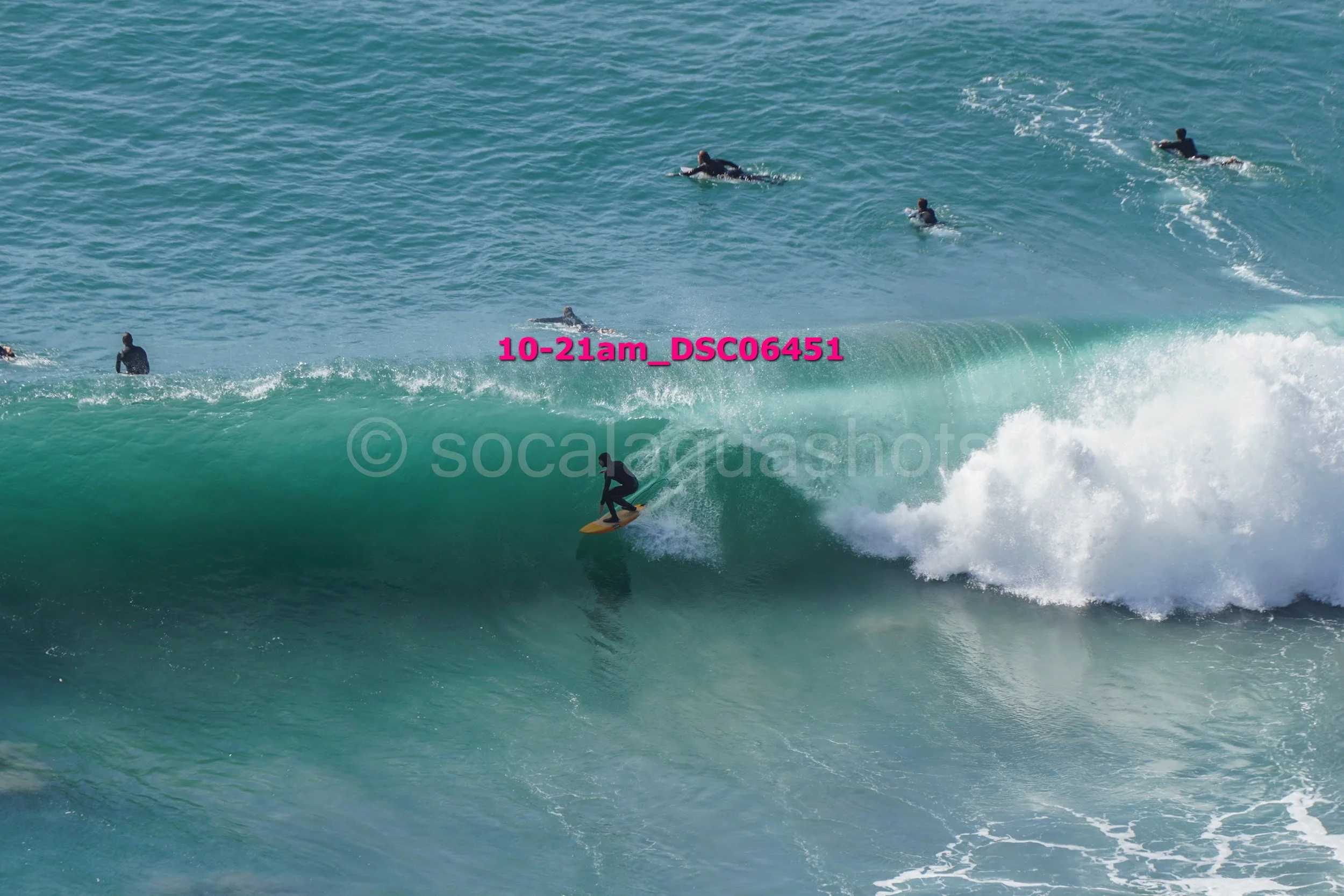 Surfer riding a wave with several surfers in the background in the ocean.