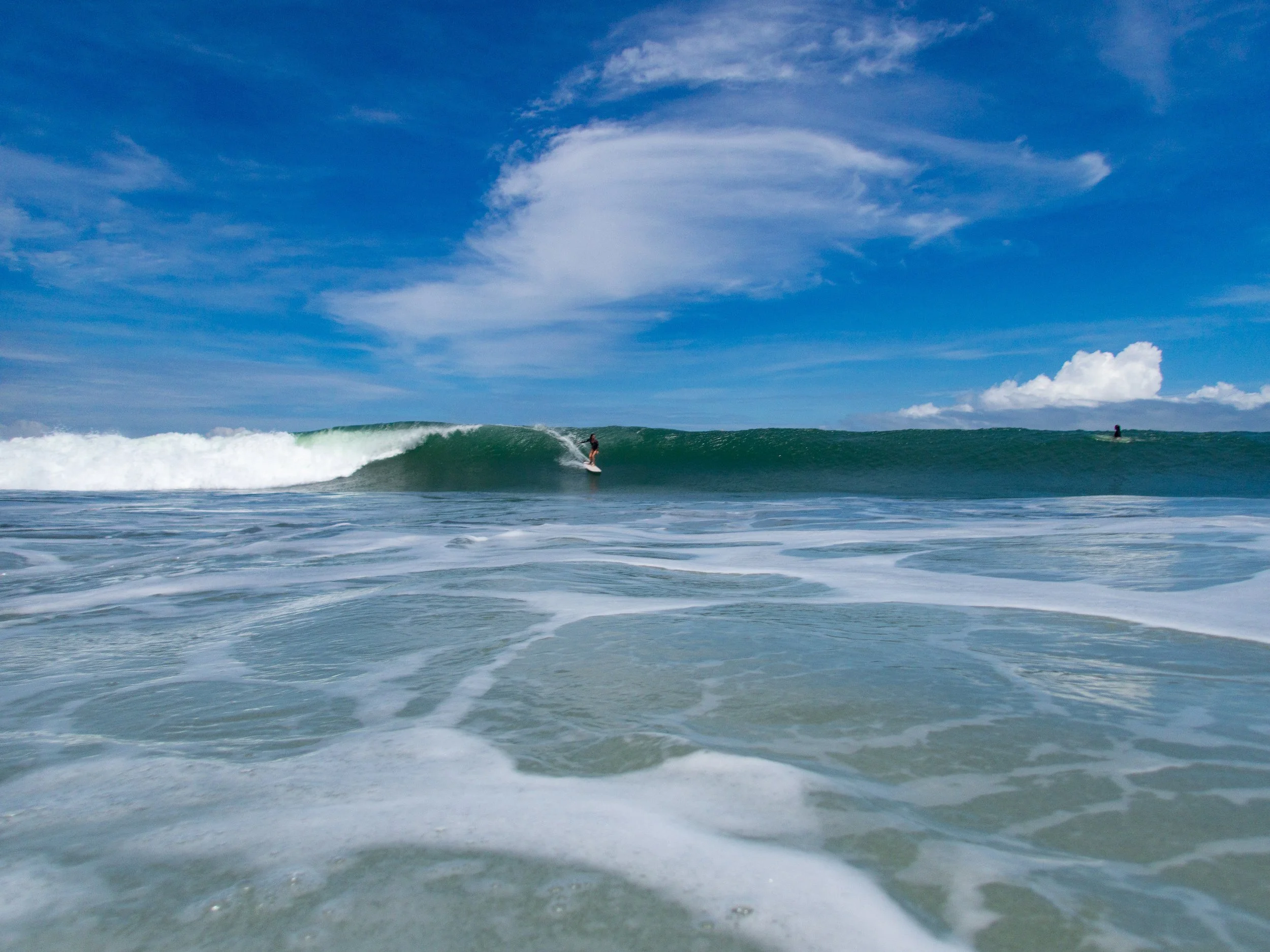 surfer riding a wave under a blue sky