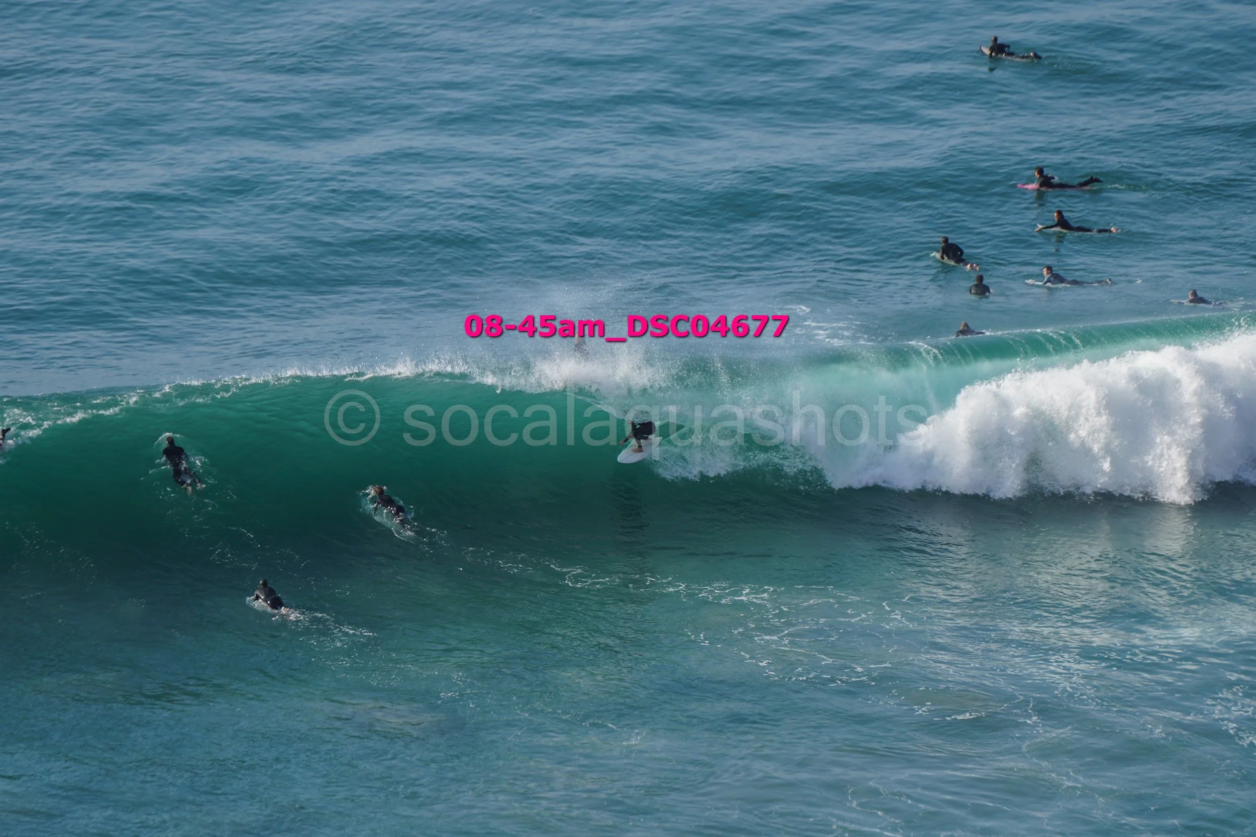 A group of surfers riding and paddling in the ocean waves.