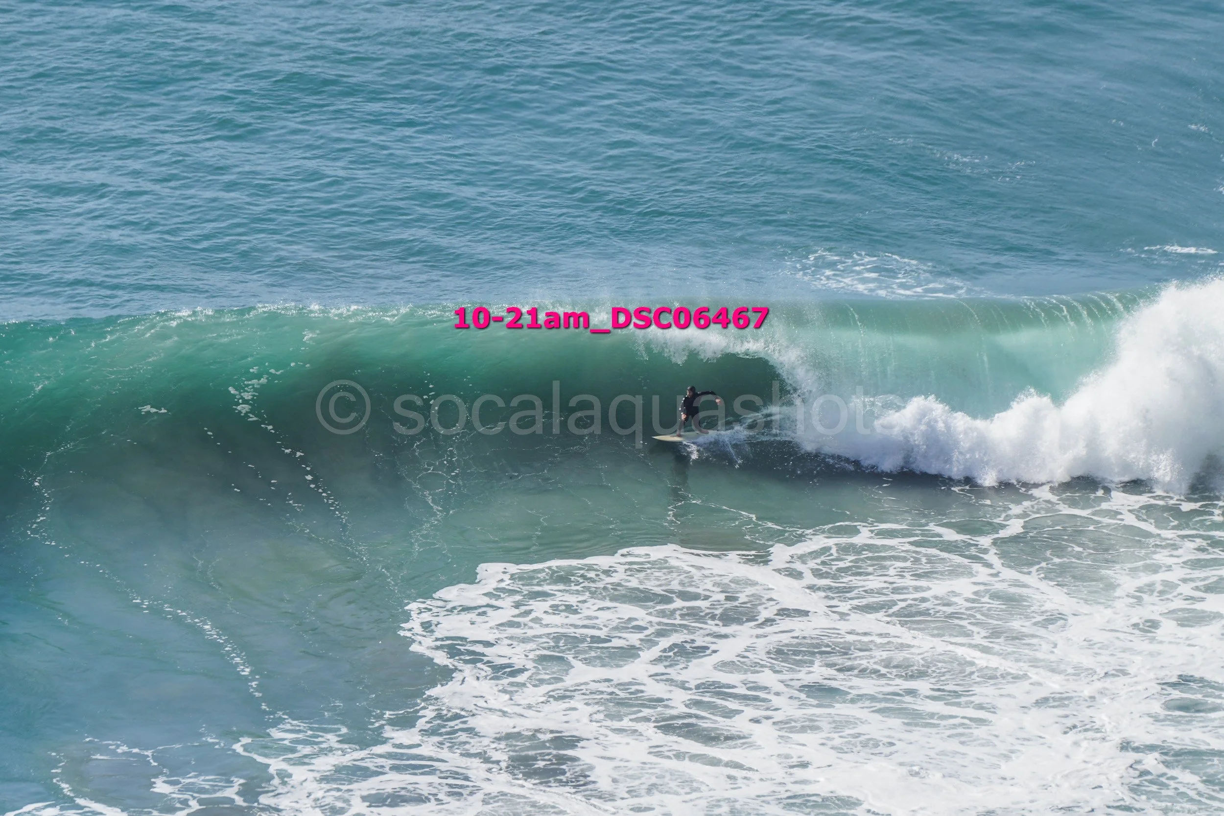 A person surfing on a large breaking wave in the ocean during daytime.