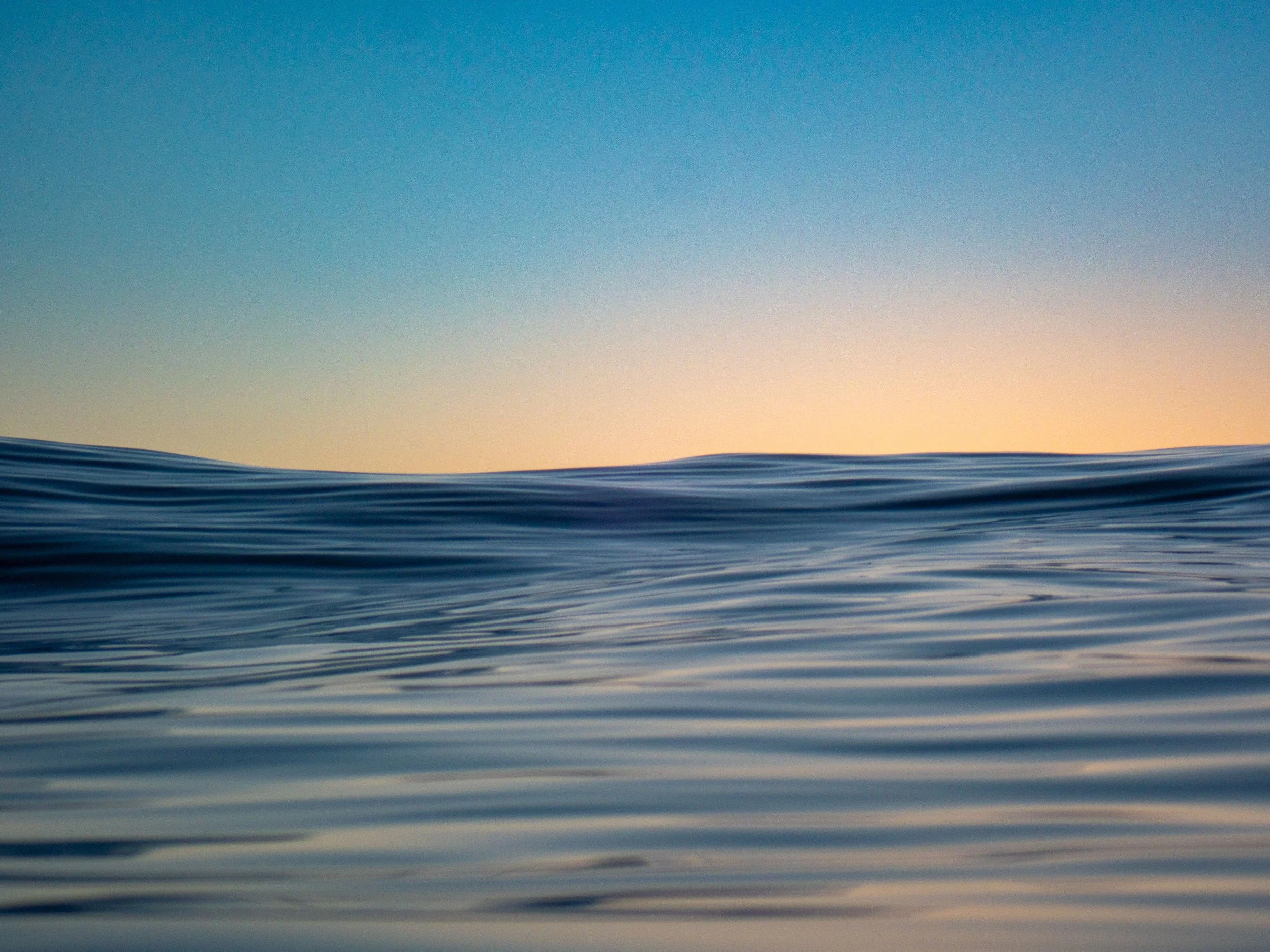 Calm ocean water during sunset with a clear sky