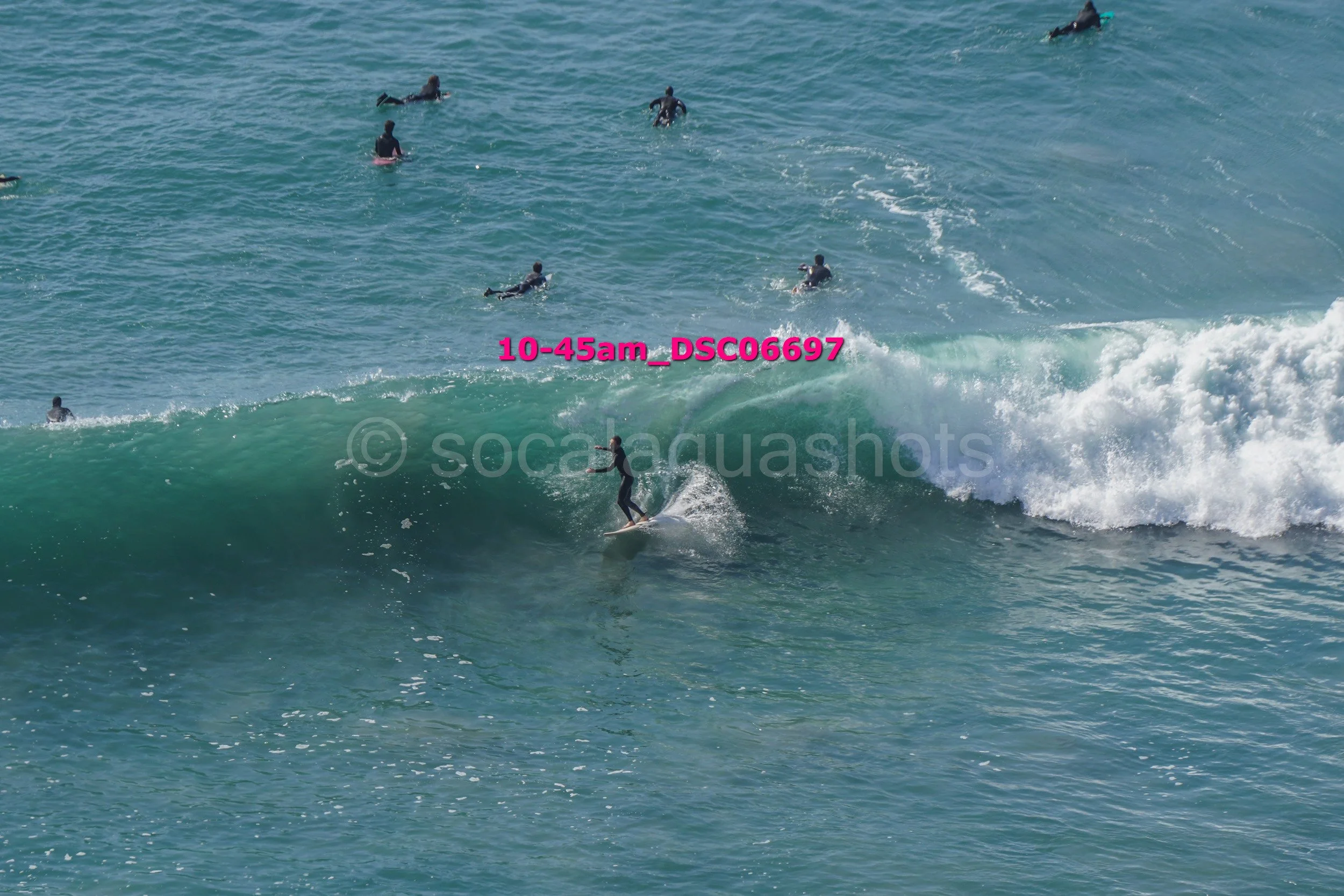 Surfer riding a wave with several surfers in the water in the background.