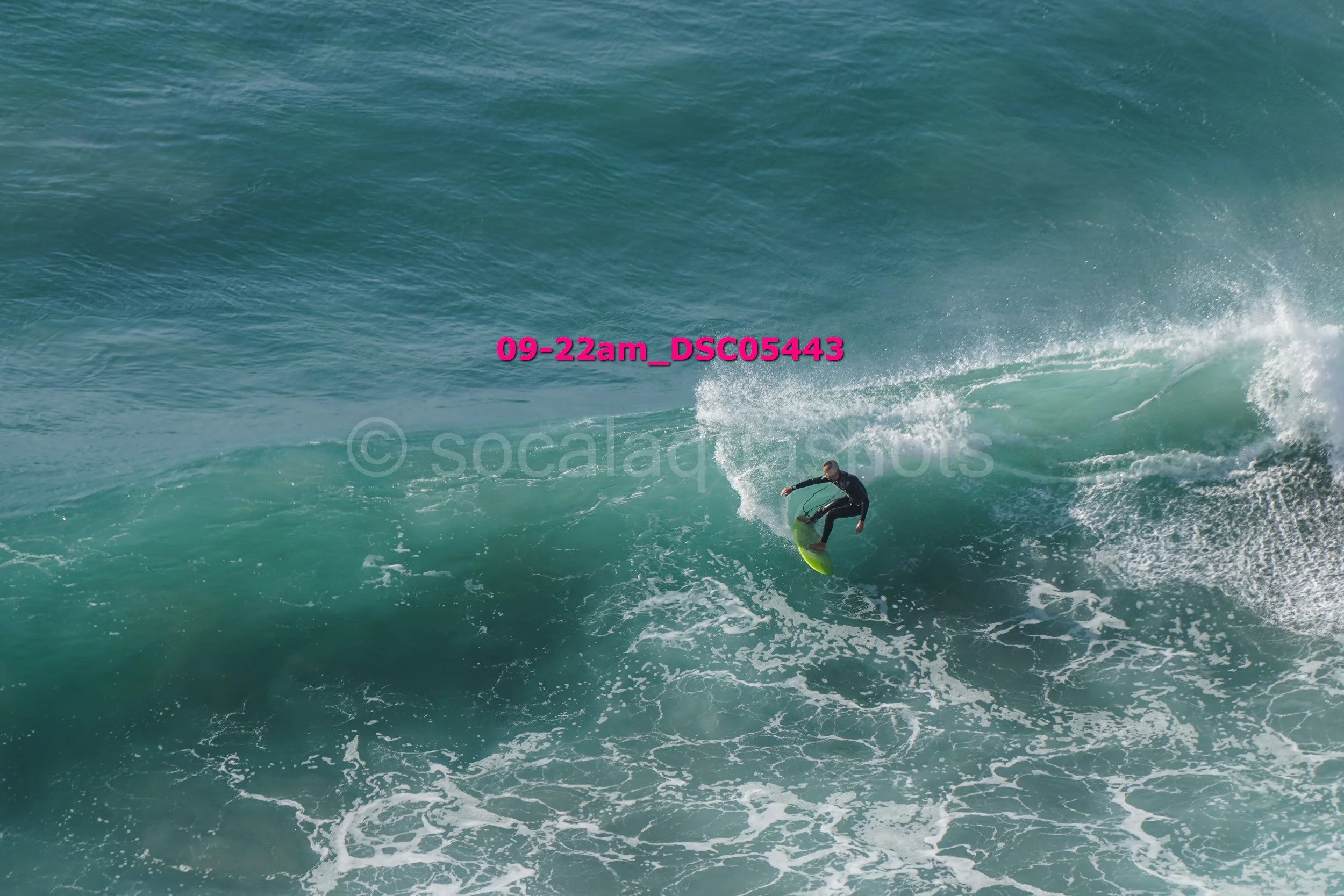 A person surfing on a wave in the ocean, wearing a black wetsuit, performing a maneuver on a yellow surfboard.