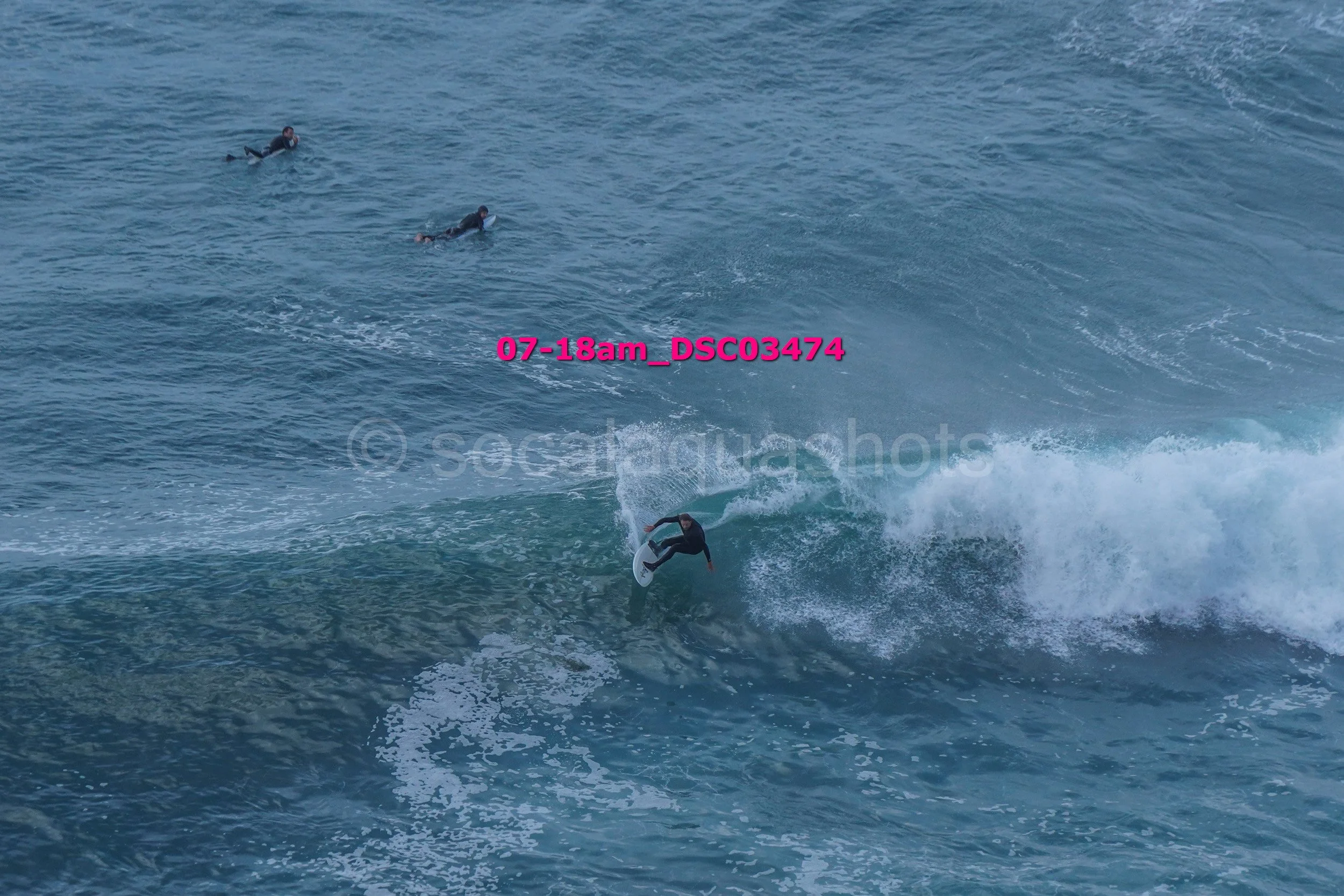 Surfer riding a wave with three other surfers in the water nearby.