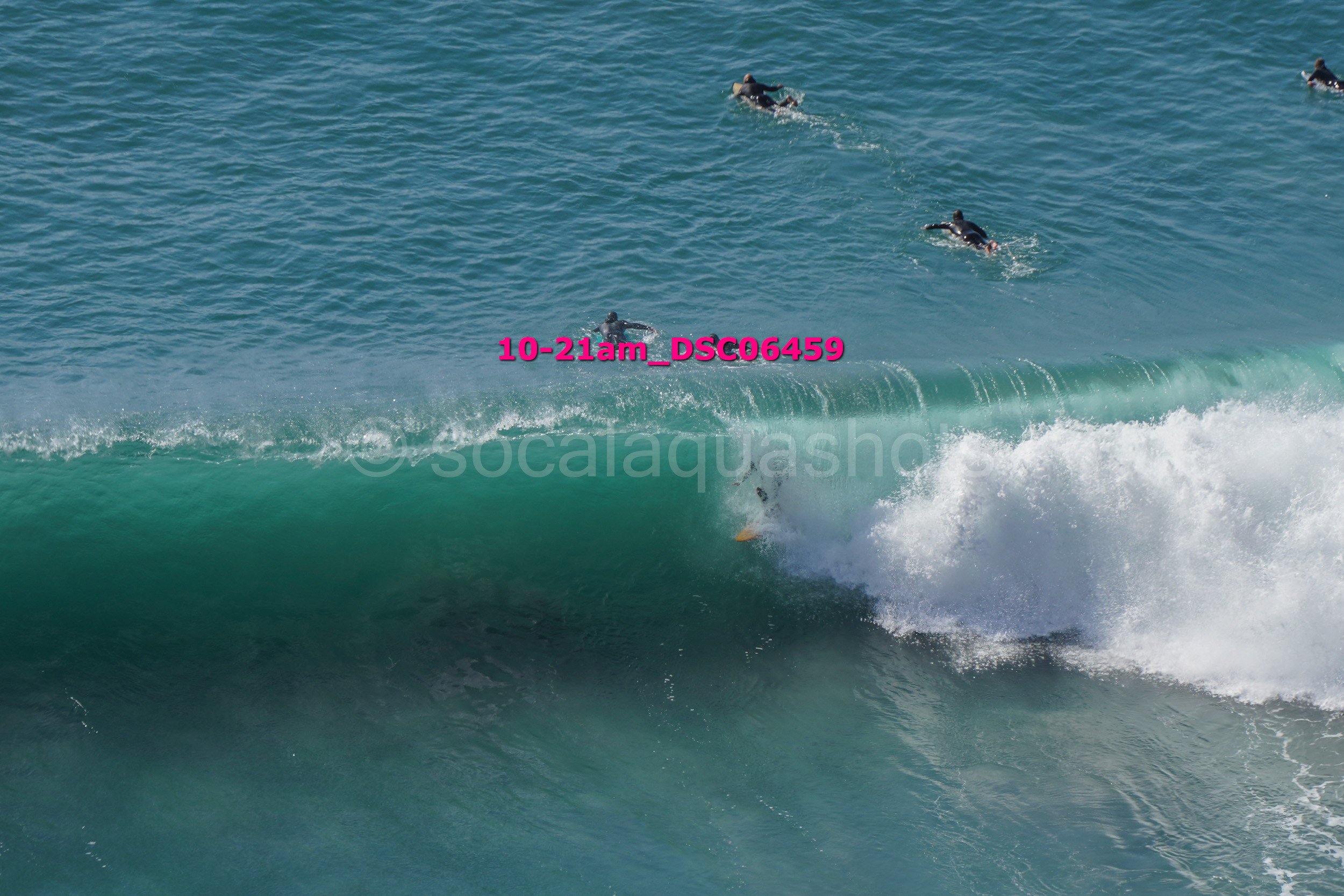 People surfing on ocean waves with one surfer partially submerged under the wave.