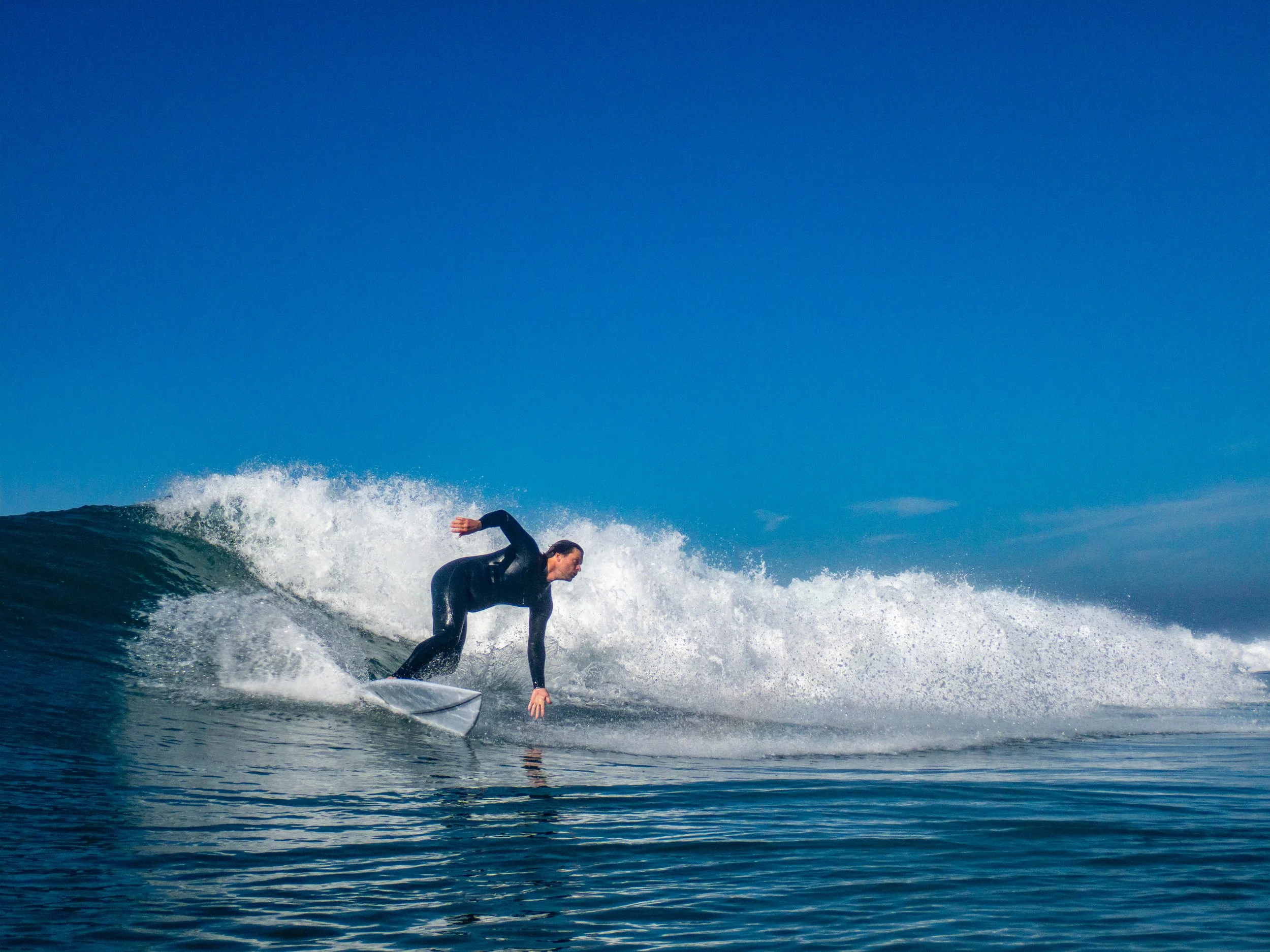 A person in a wetsuit riding a surfboard on a wave in the ocean.