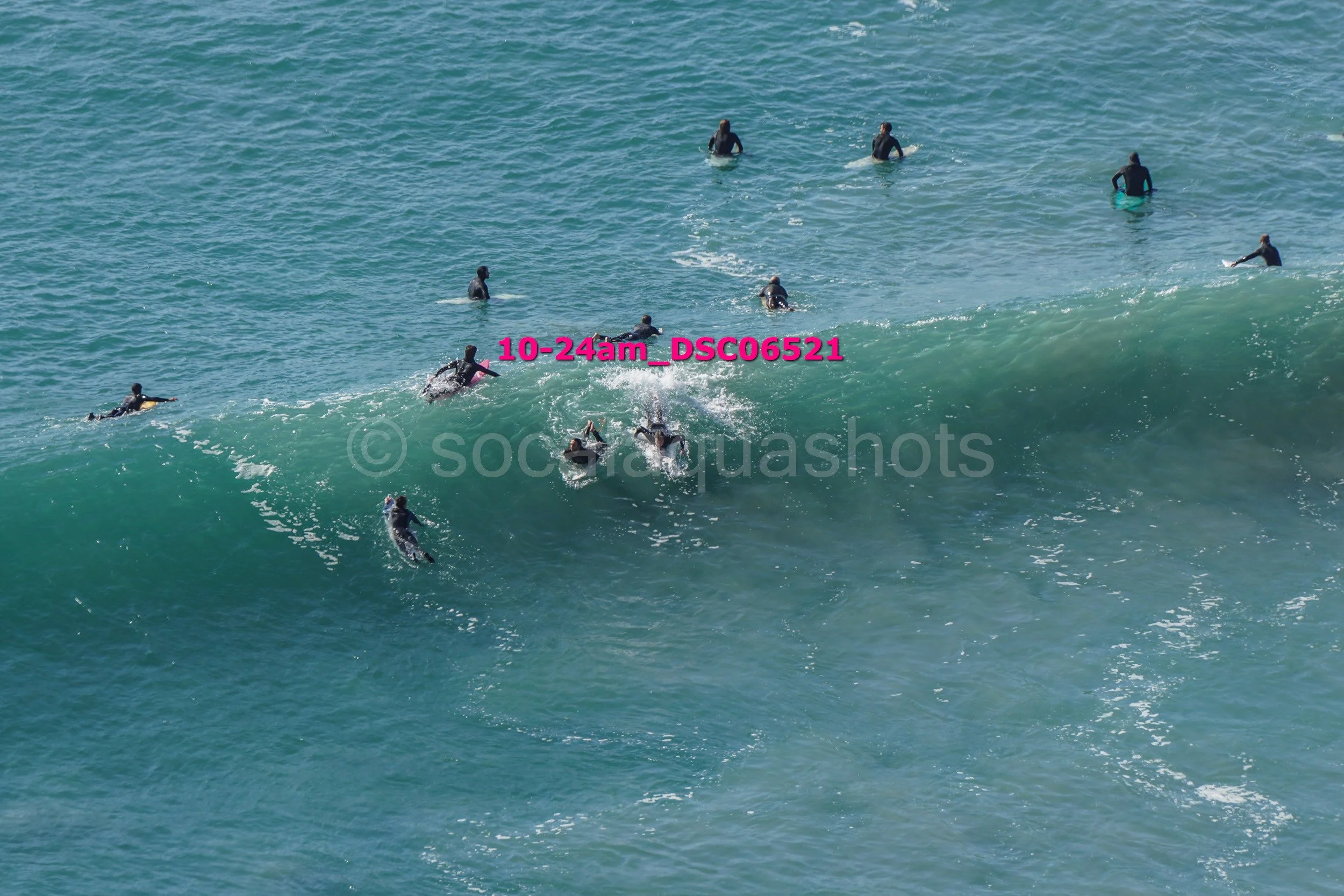 Multiple surfers in wetsuits surfing and paddling on ocean waves.