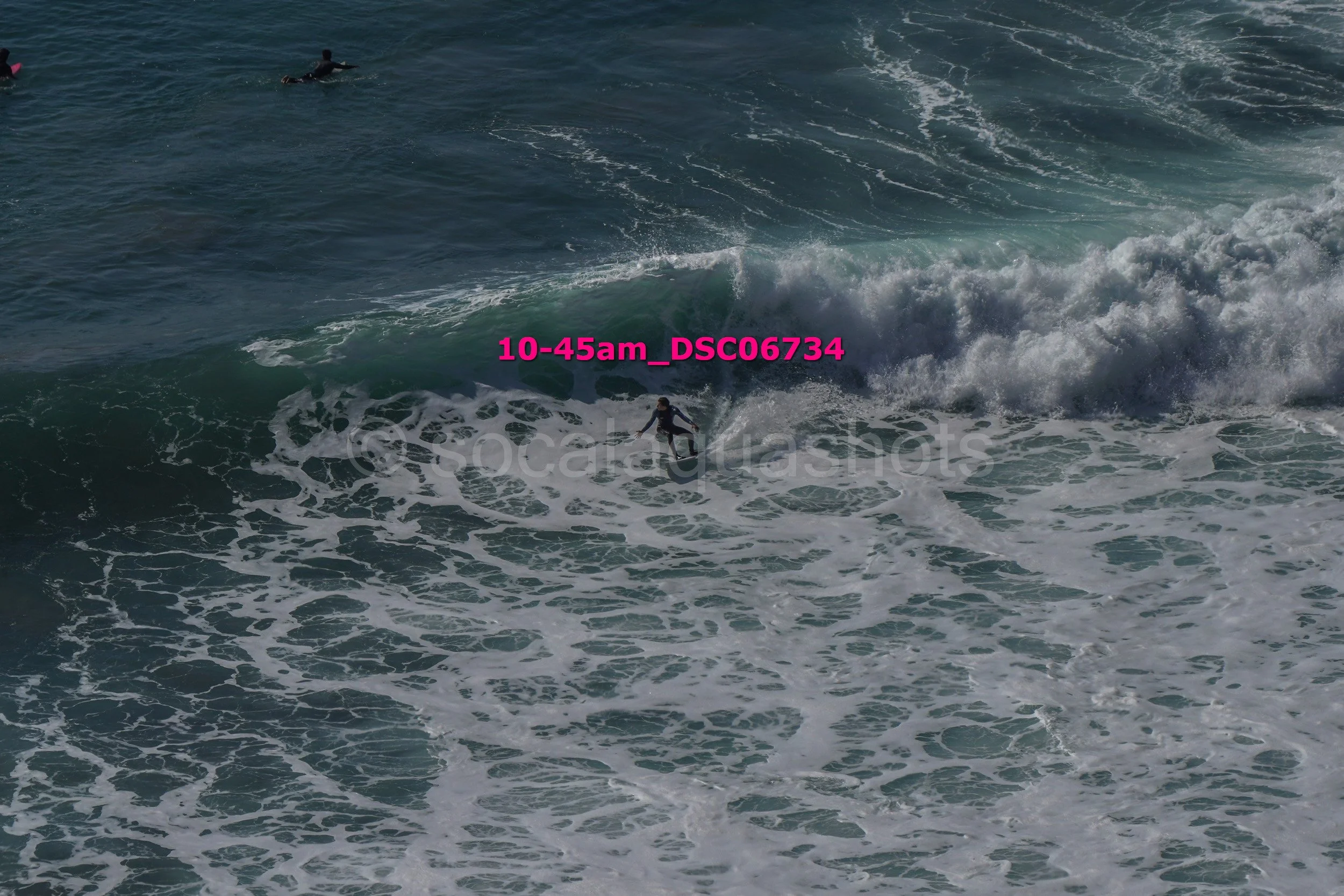 Surfer riding a wave in the ocean with two other surfers in the background