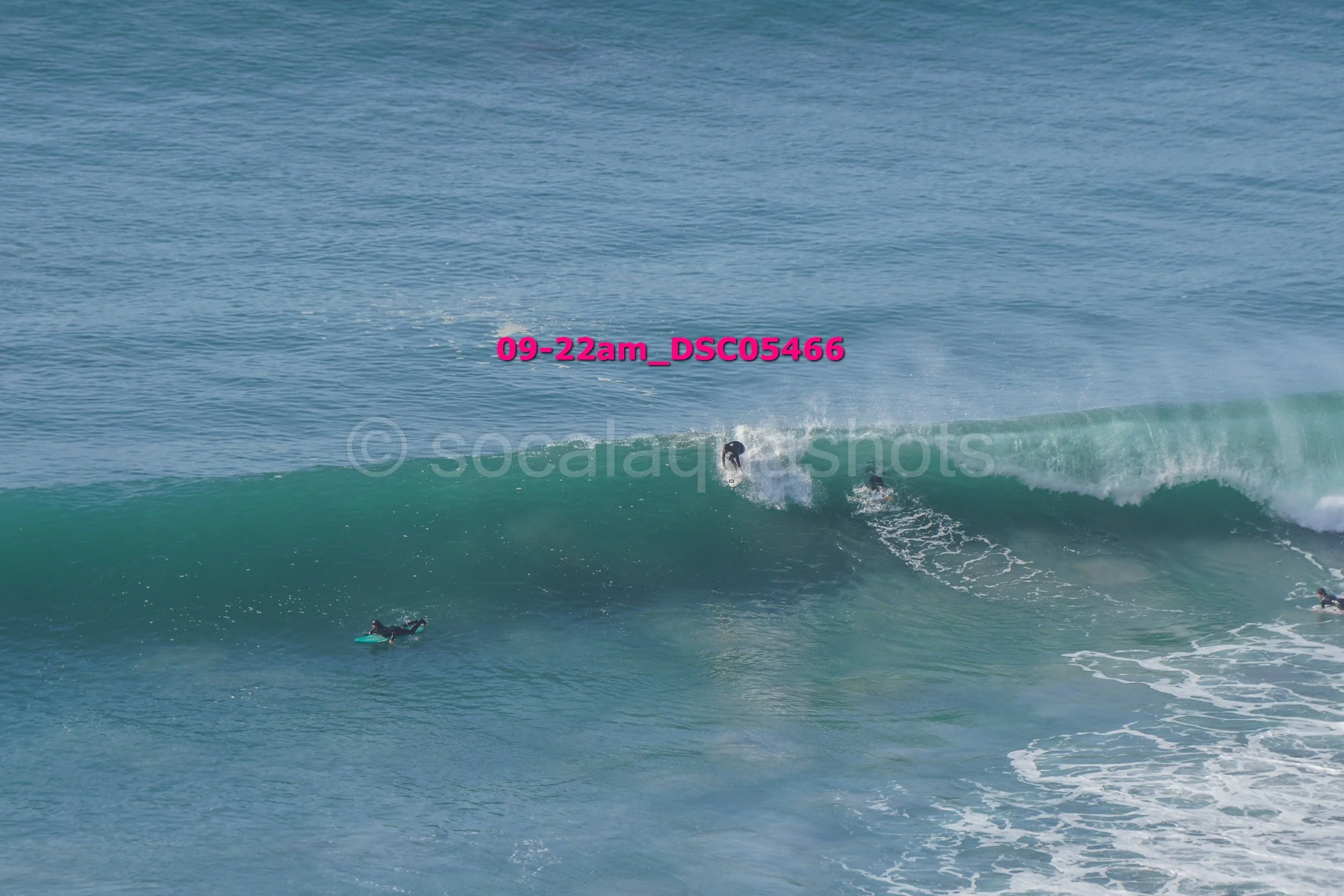 Surfers riding blue-green waves in the ocean during daytime.