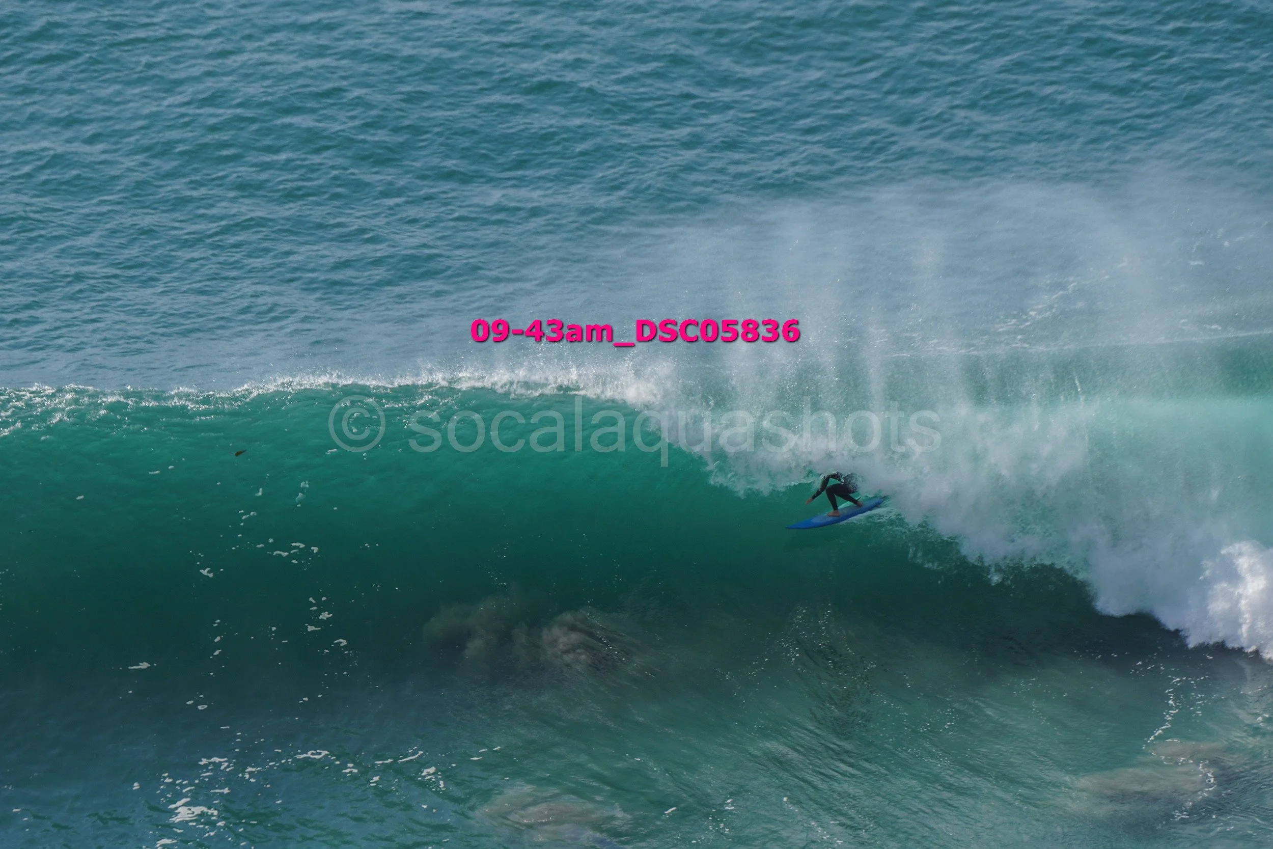 A person surfing on a large wave in the ocean during daytime.