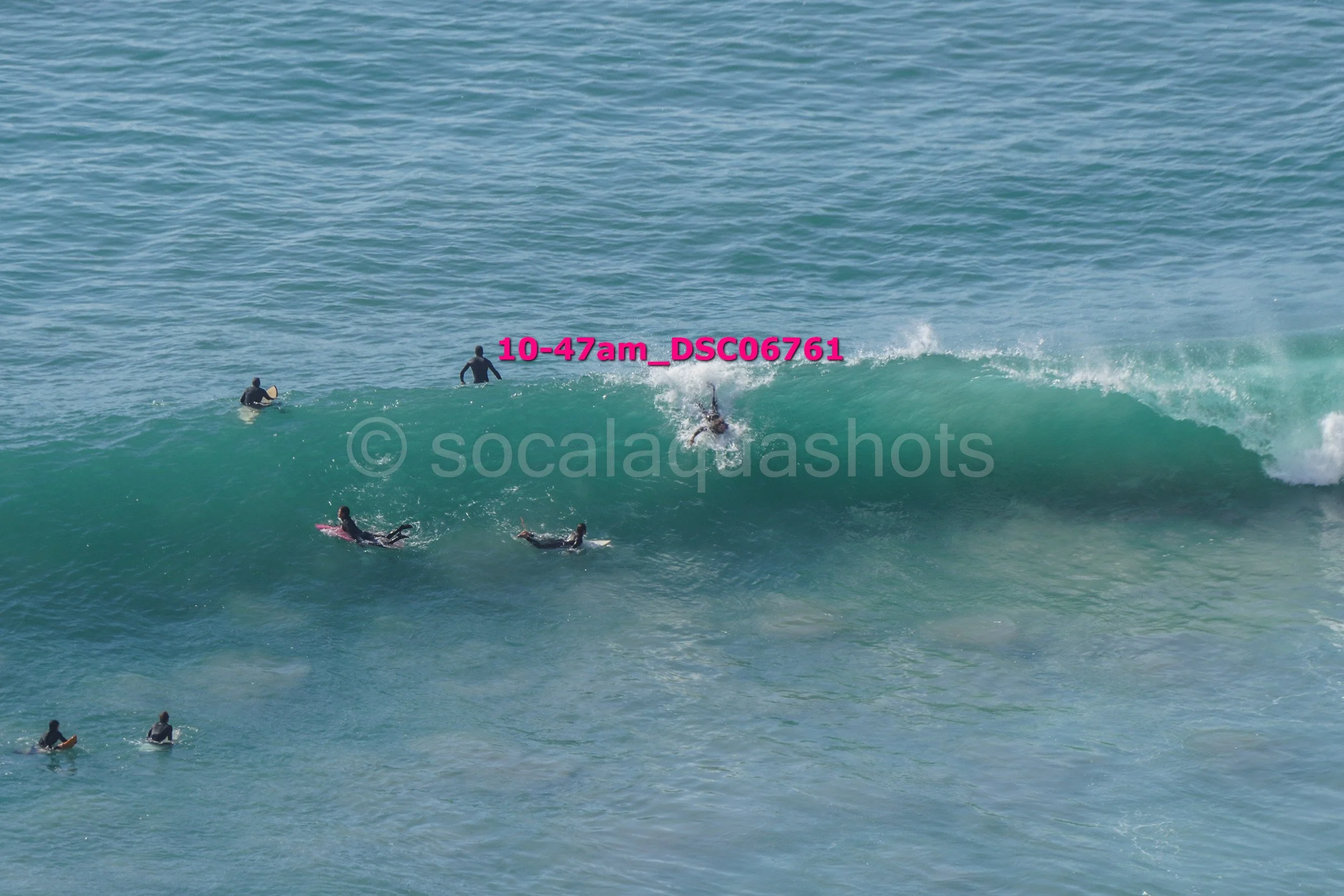 Group of people surfing in the ocean, some riding a wave and others waiting in the water