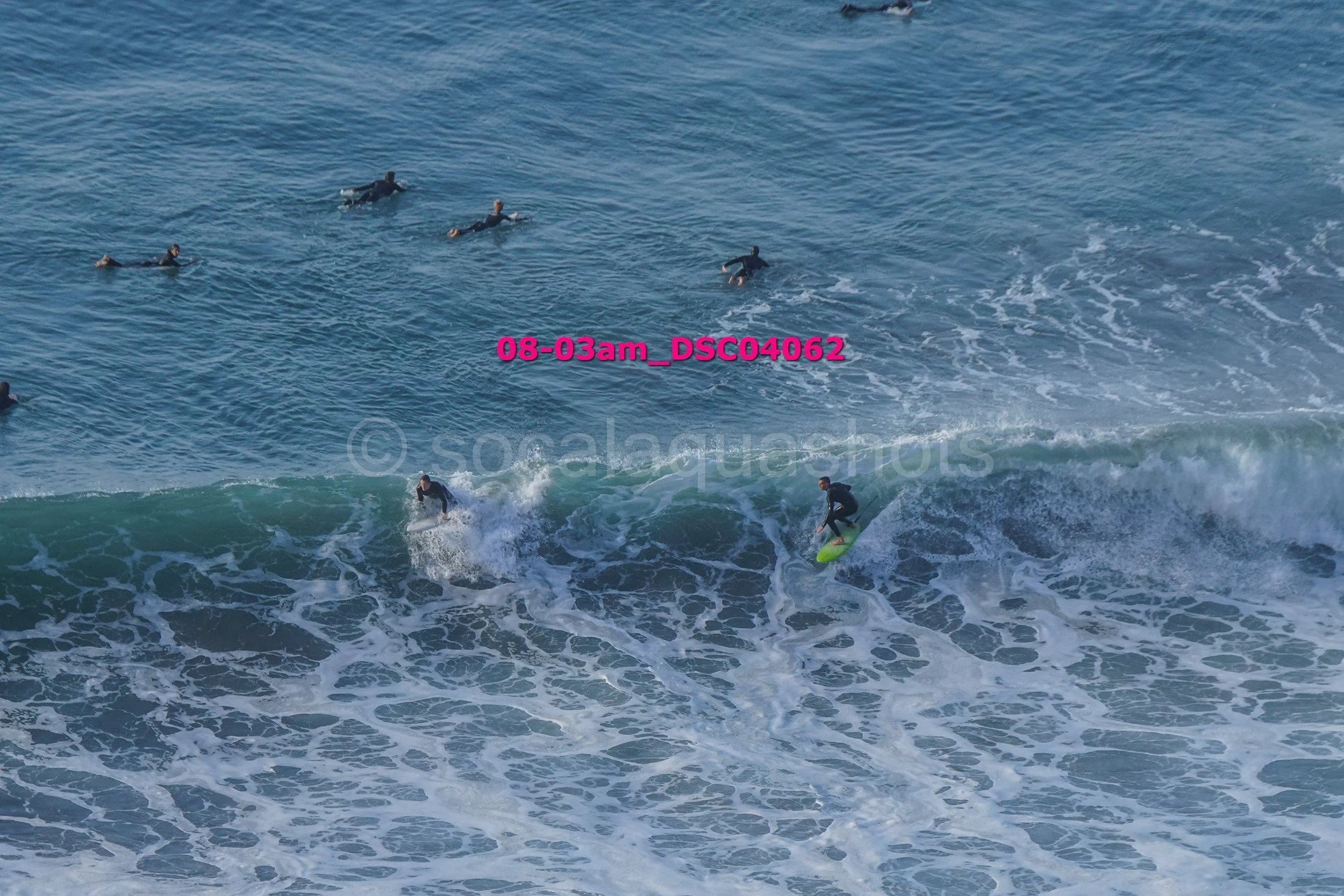 Group of people surfing and swimming in the ocean.