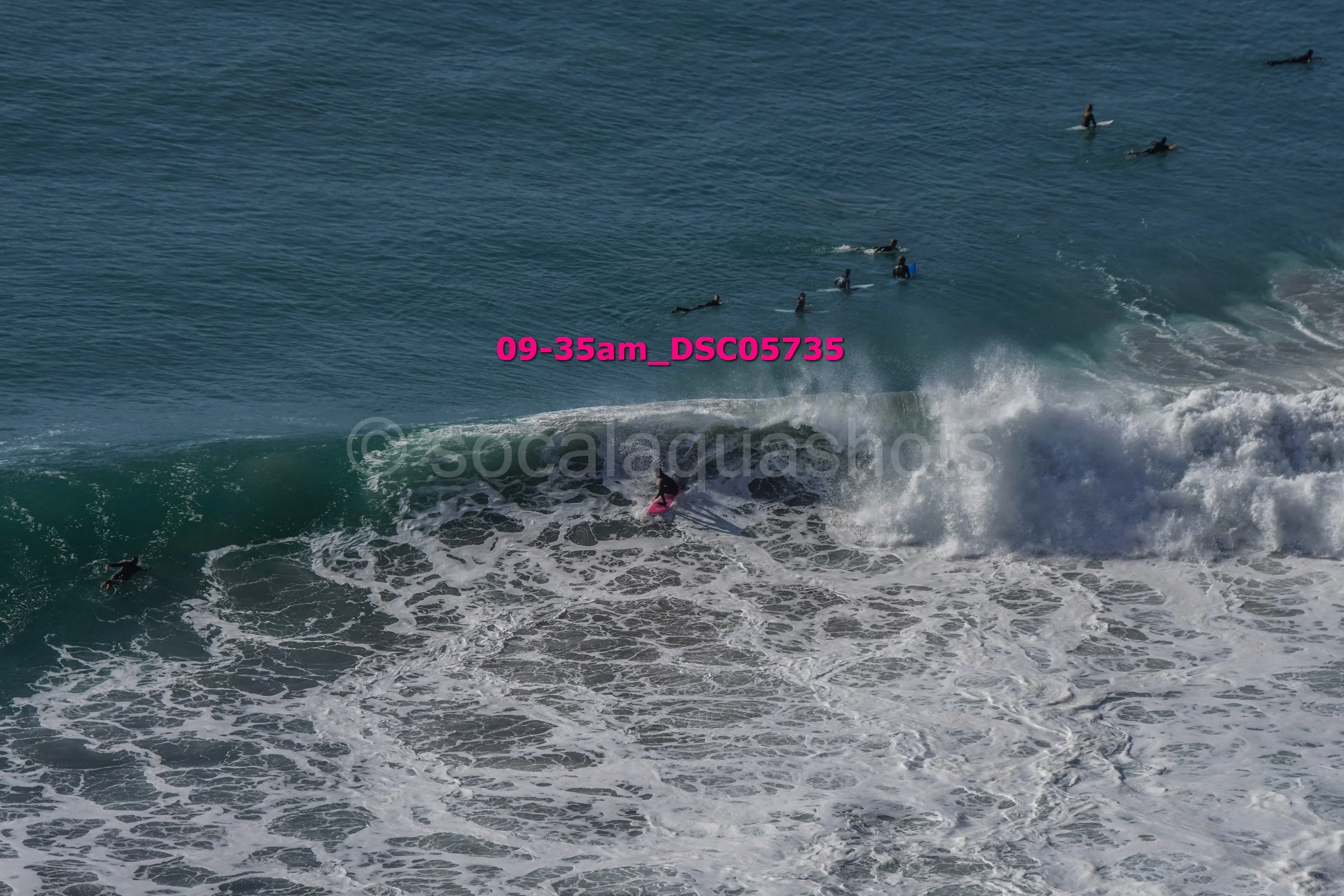 A group of surfers riding and waiting in the ocean waves during daylight hours.