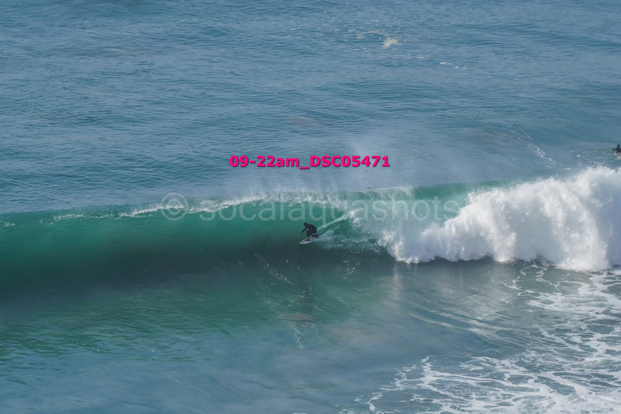 A person surfing on a wave in the ocean on a clear day.