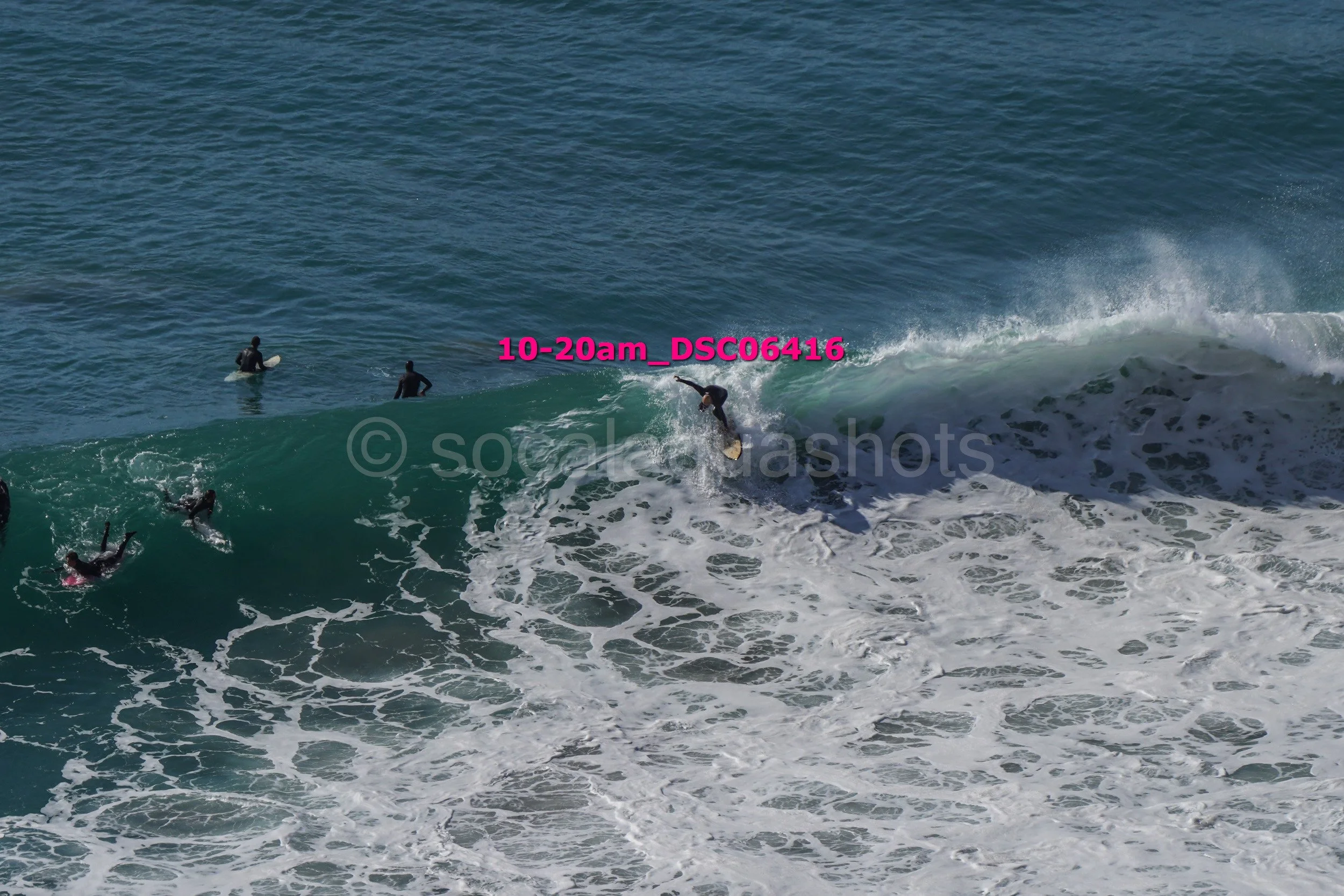 Surfer riding a wave at the beach, with other surfers in the water.