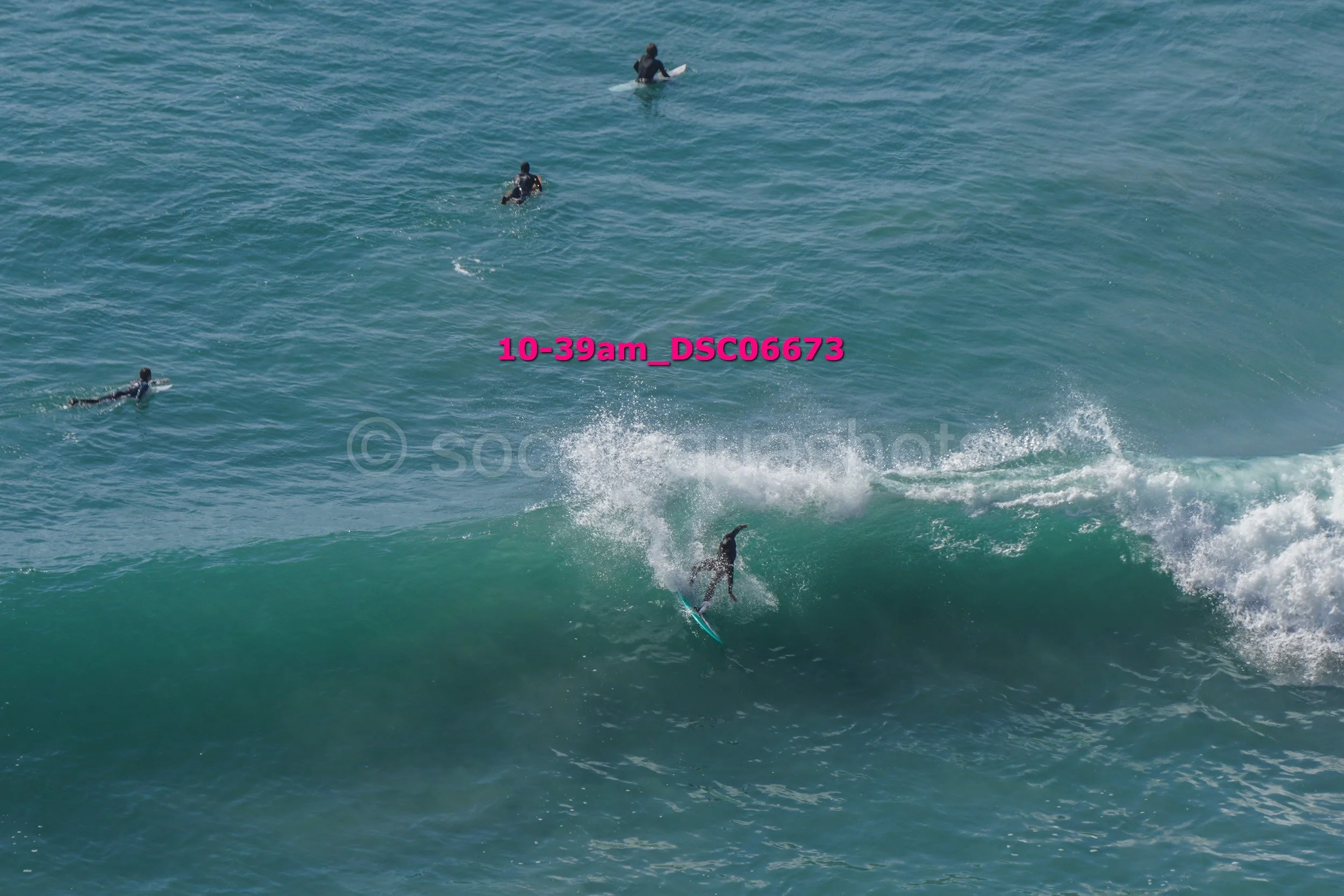 Surfer riding a wave with three other surfers in the water behind.