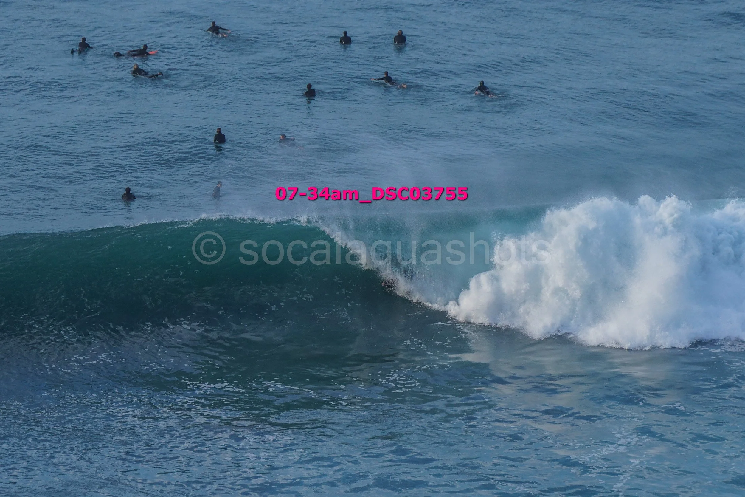 A person surfing on a wave in the ocean with several other surfers in the background.