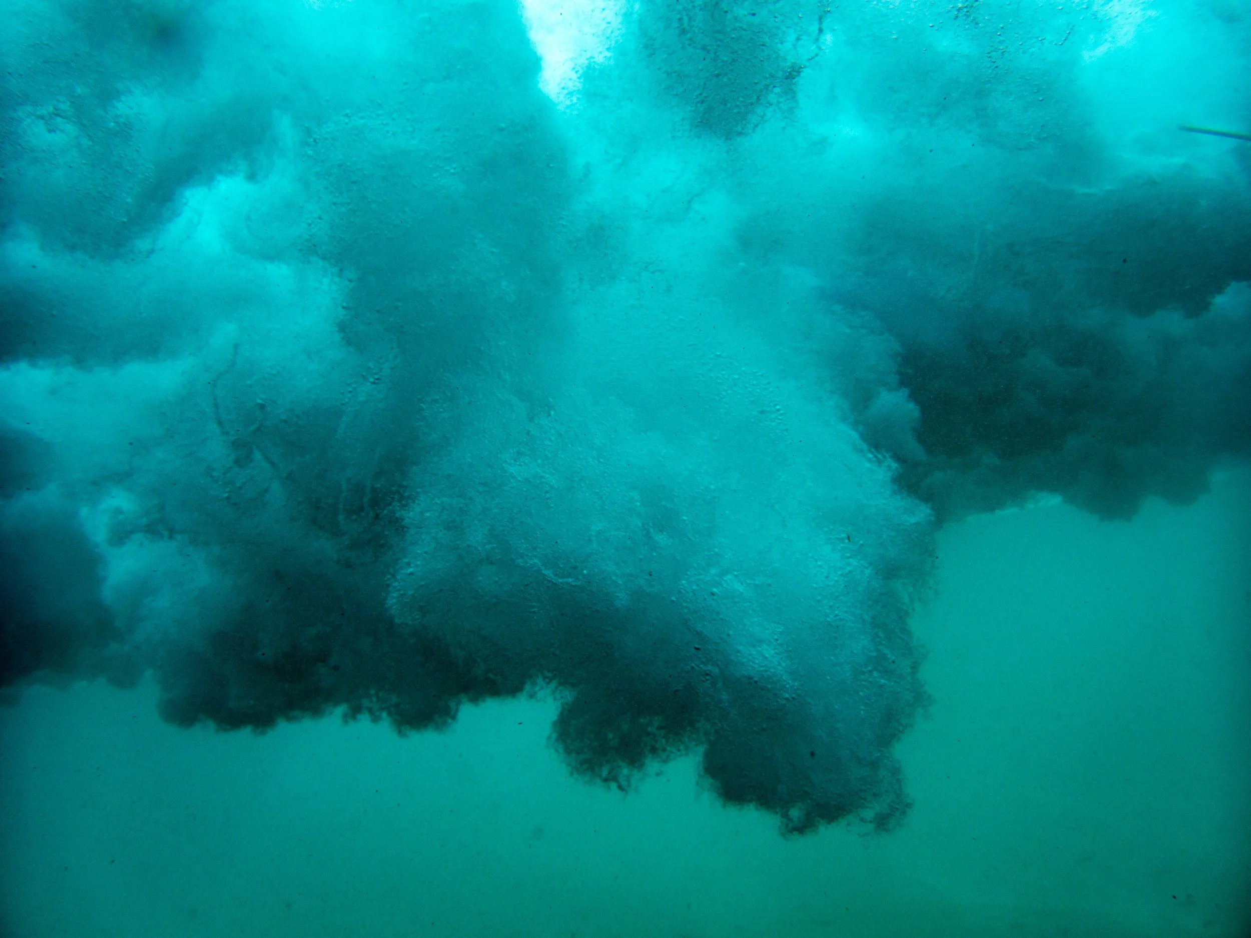Underwater view of turbulent water with bubbles and foam.