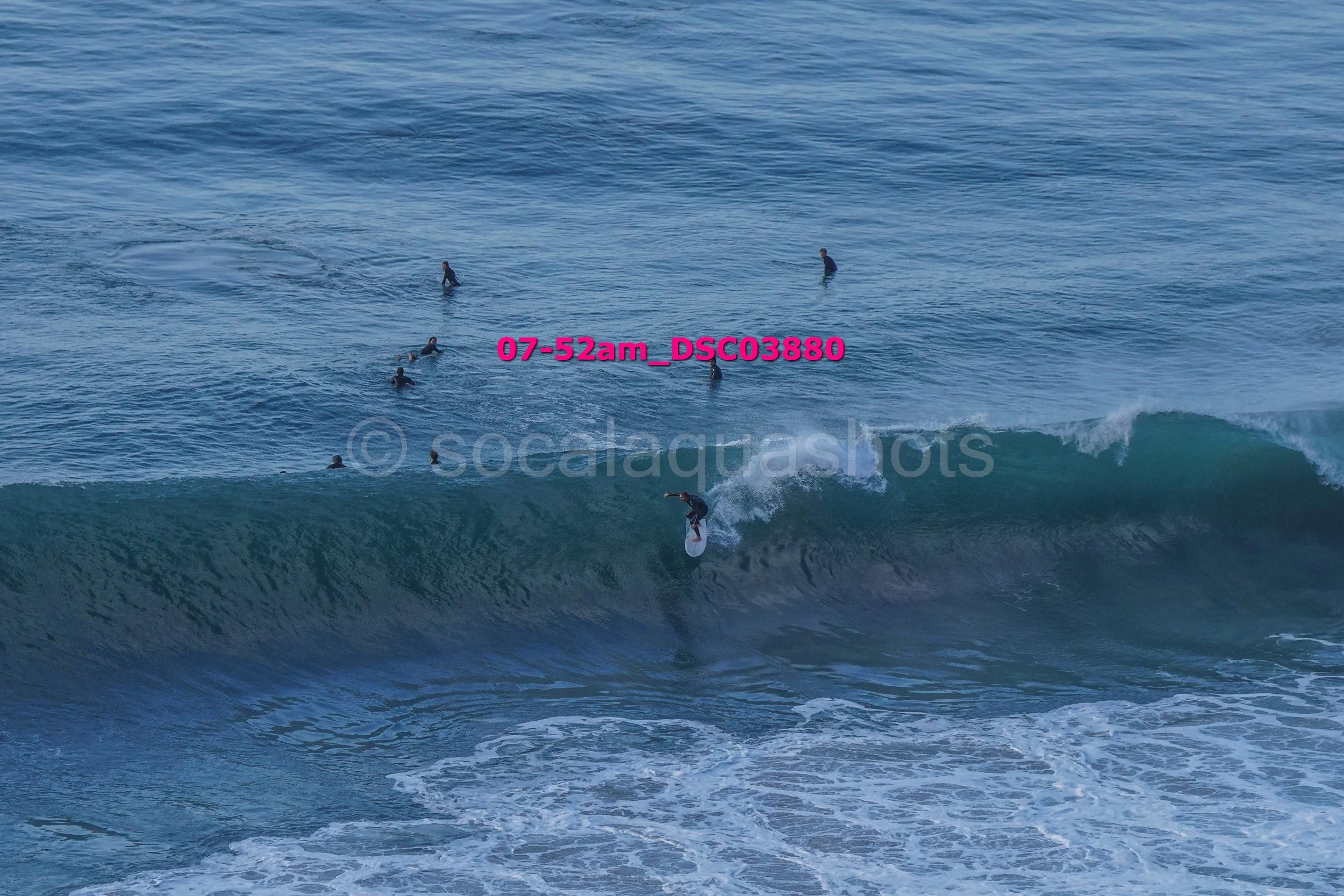 Surfer riding a wave with multiple surfers in the water in the background.