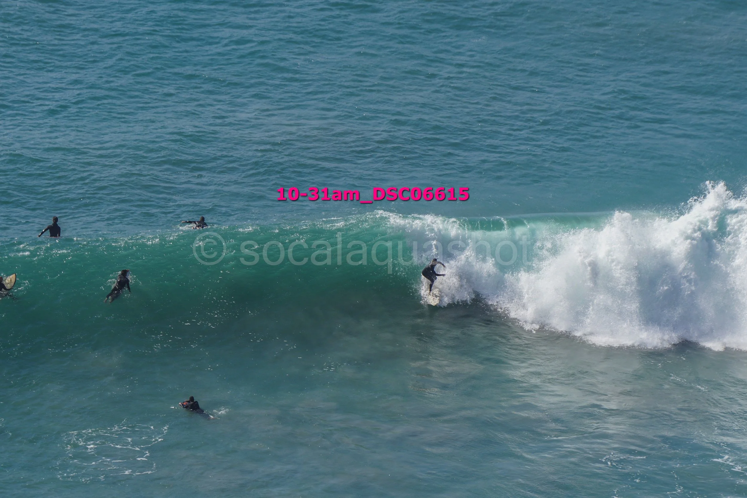 Surfer riding a wave with multiple surfers in the water observing amid ocean waves