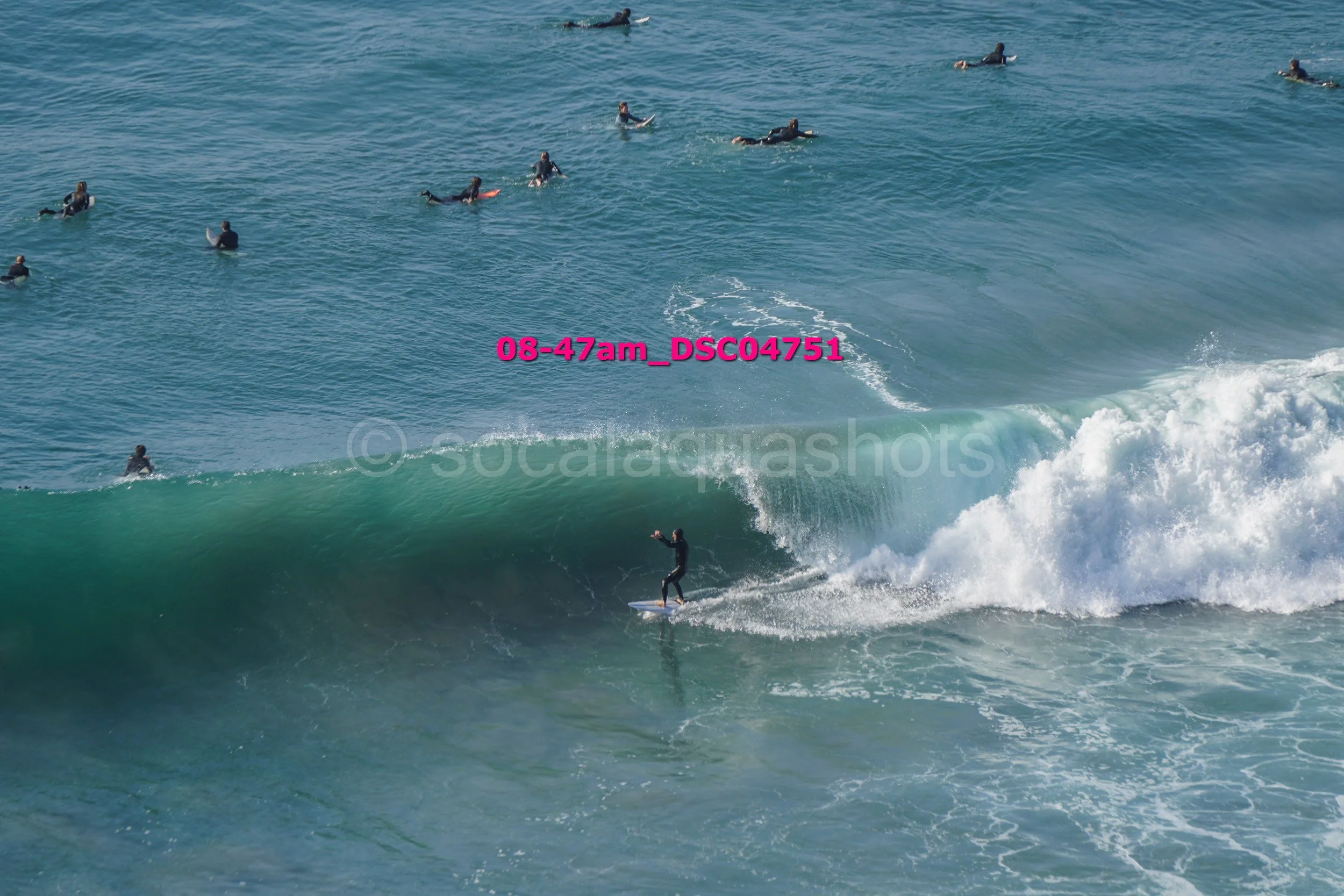 A person surfing a wave with other surfers in the water nearby.