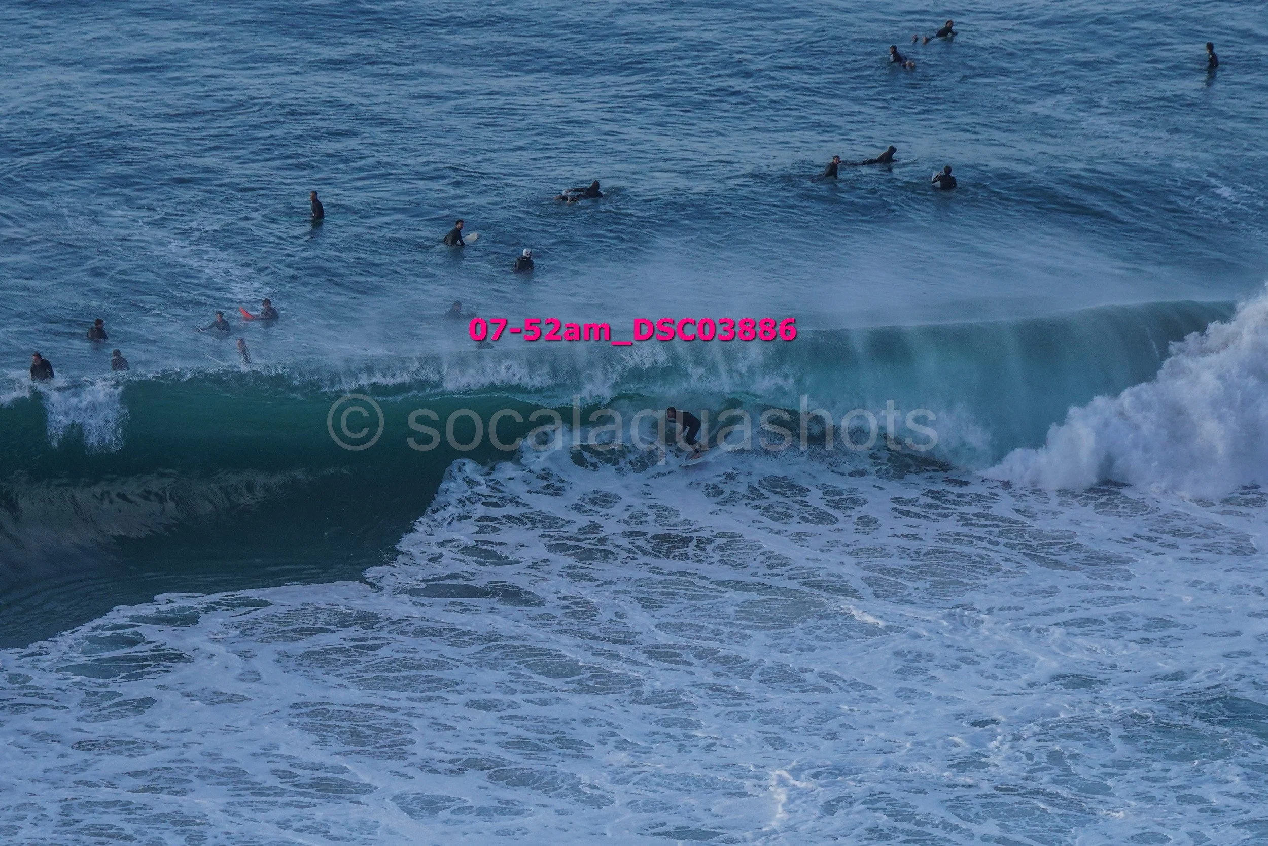 A group of people swimming and surfing in the ocean, with one person riding a wave.