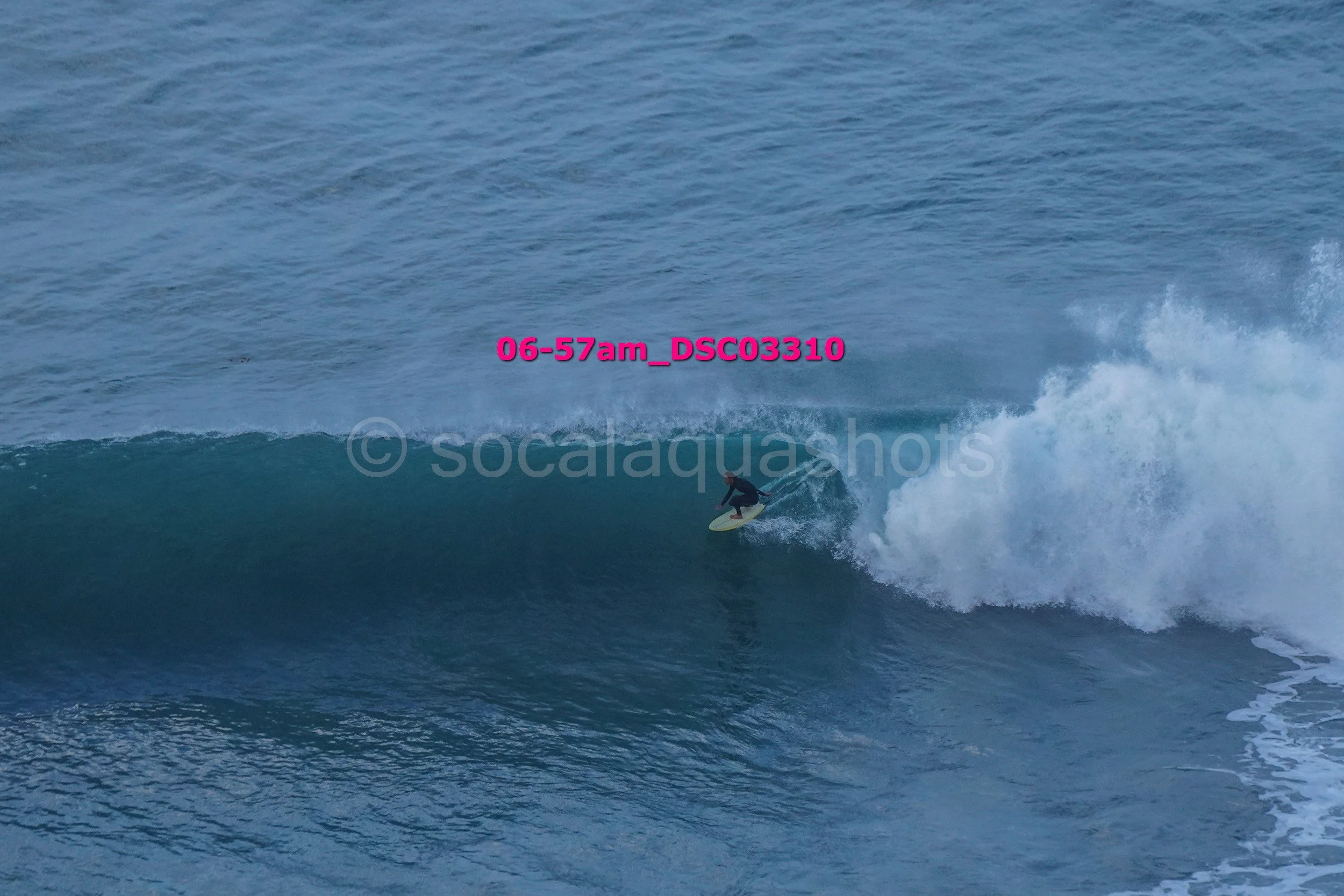 A person surfing on a large wave in the ocean during daylight.