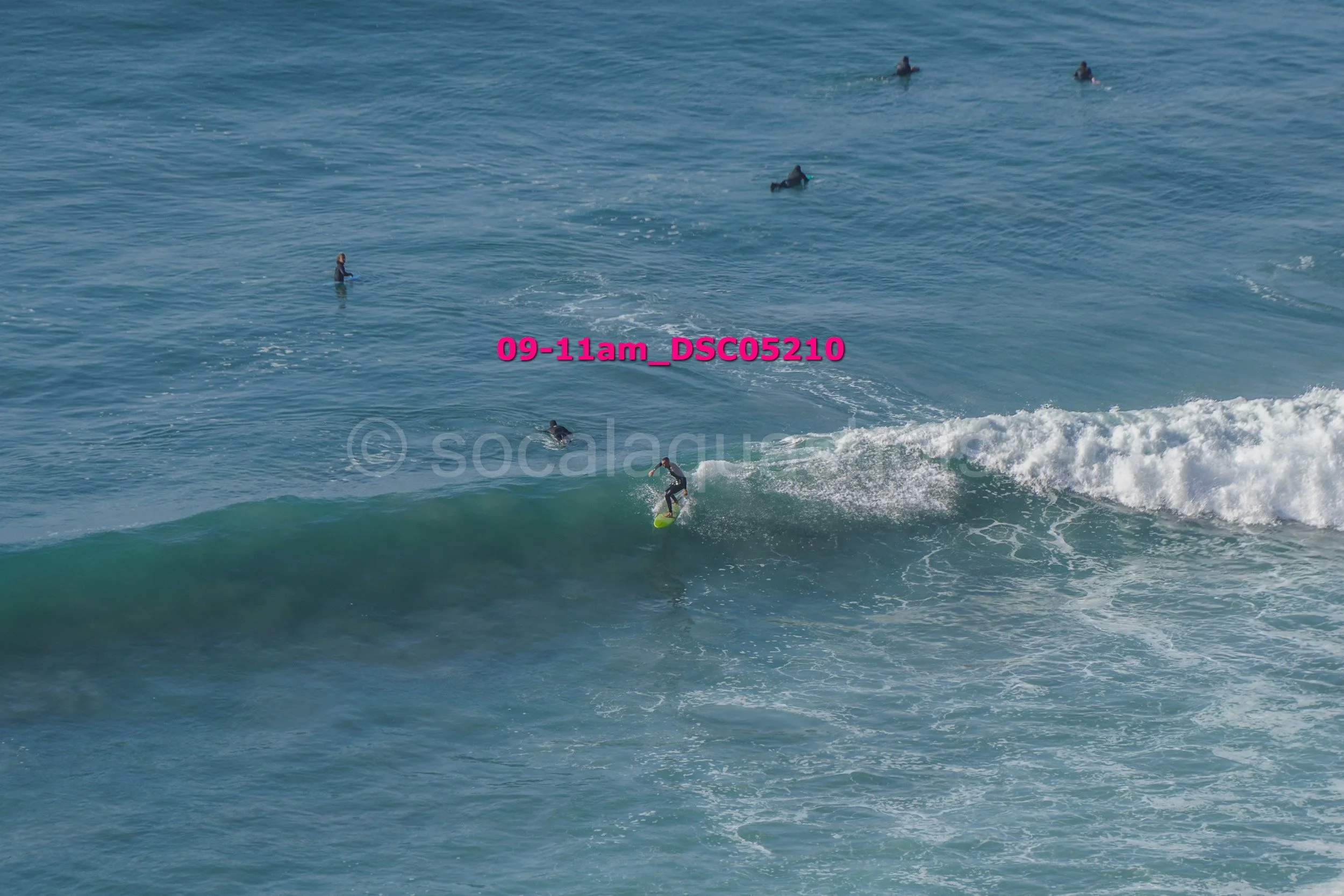 A person surfing on a wave in the ocean with several other surfers in the background.