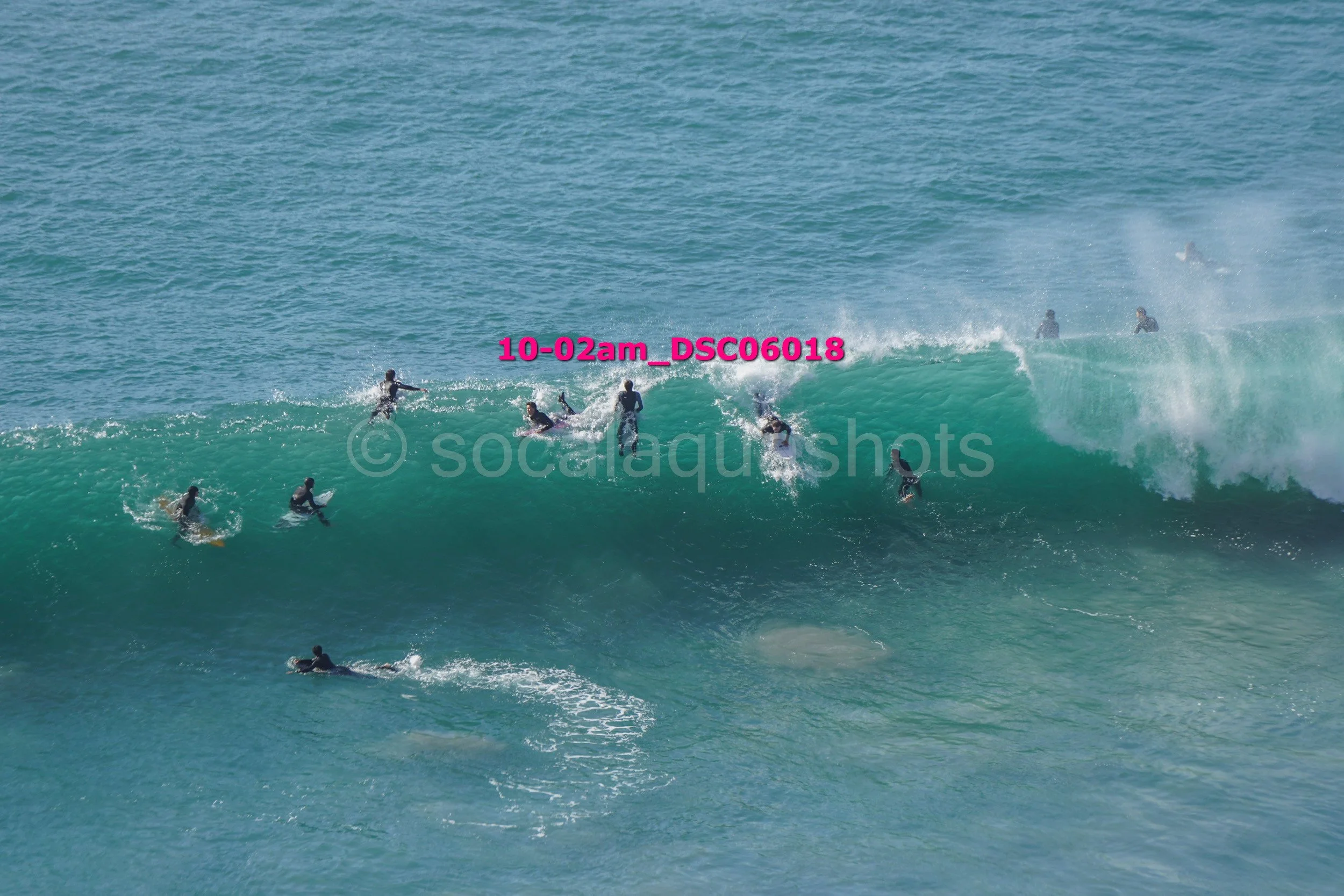 Multiple people surfing on large ocean waves in the daytime.