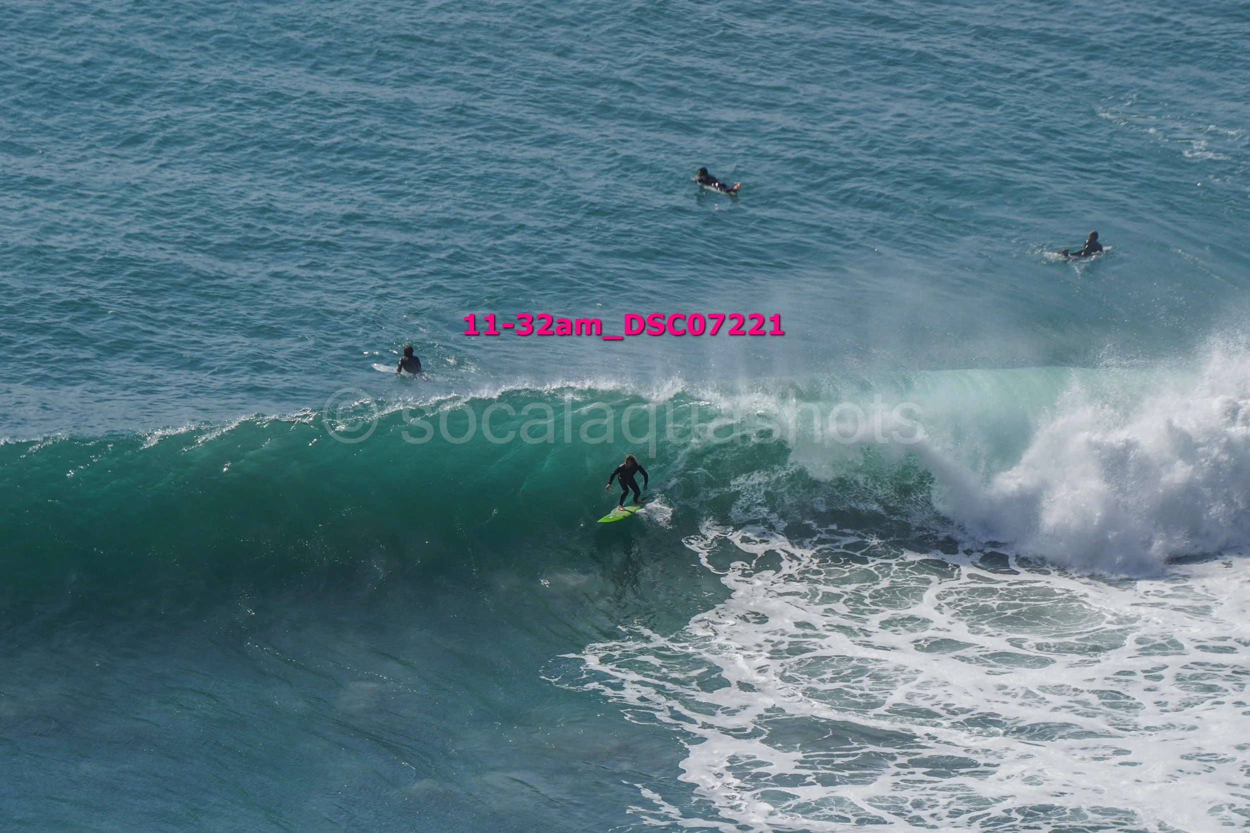 A surfer riding a wave with three people swimming in the water in the background.