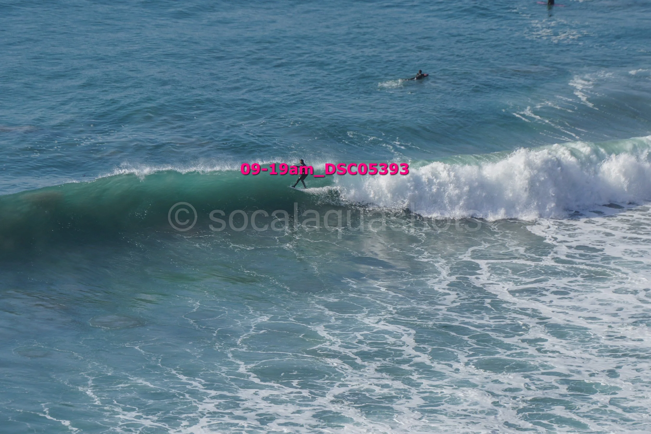 A person surfing on a wave in the ocean with a motorcycle in the background.