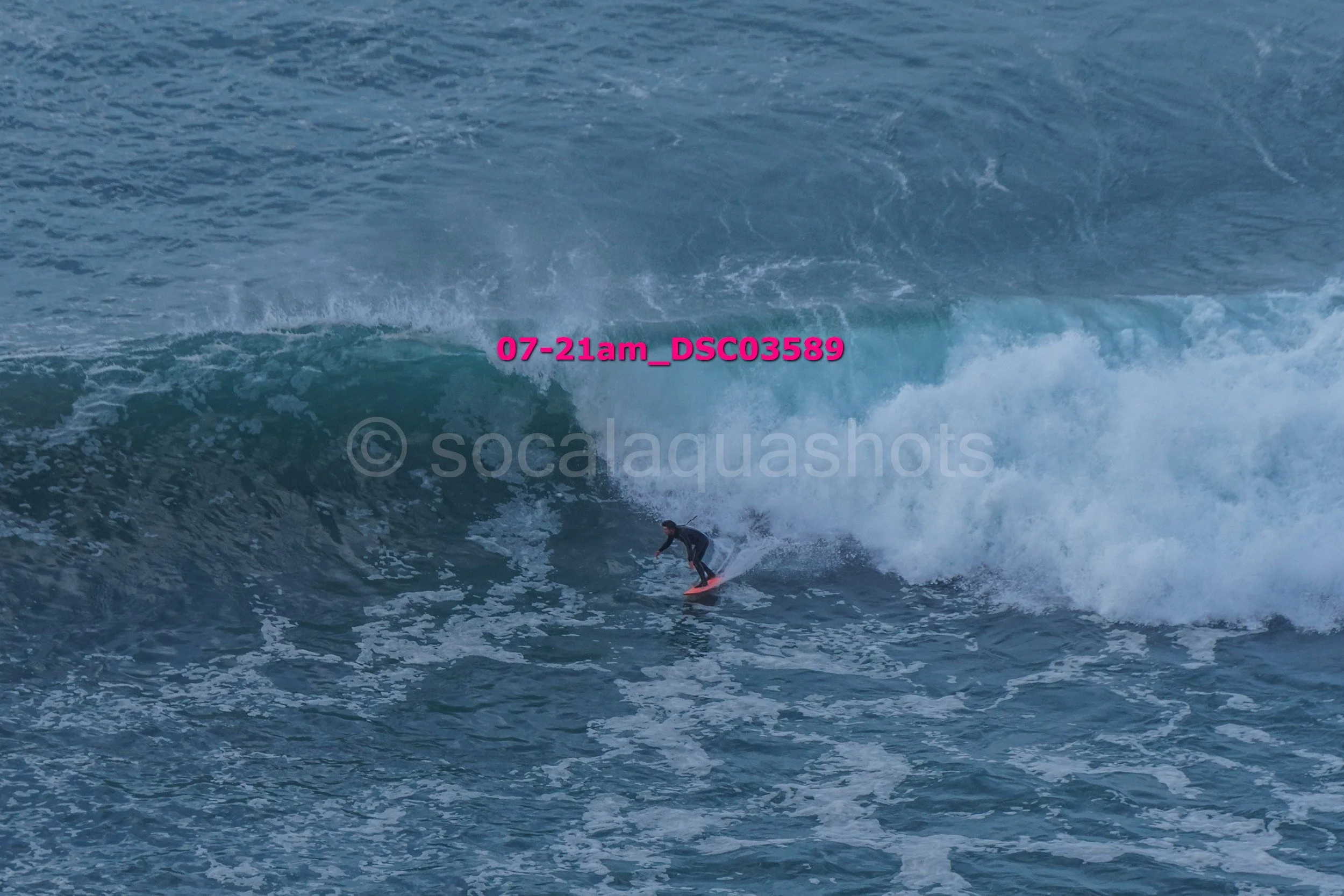 A person surfing on a large wave in the ocean.