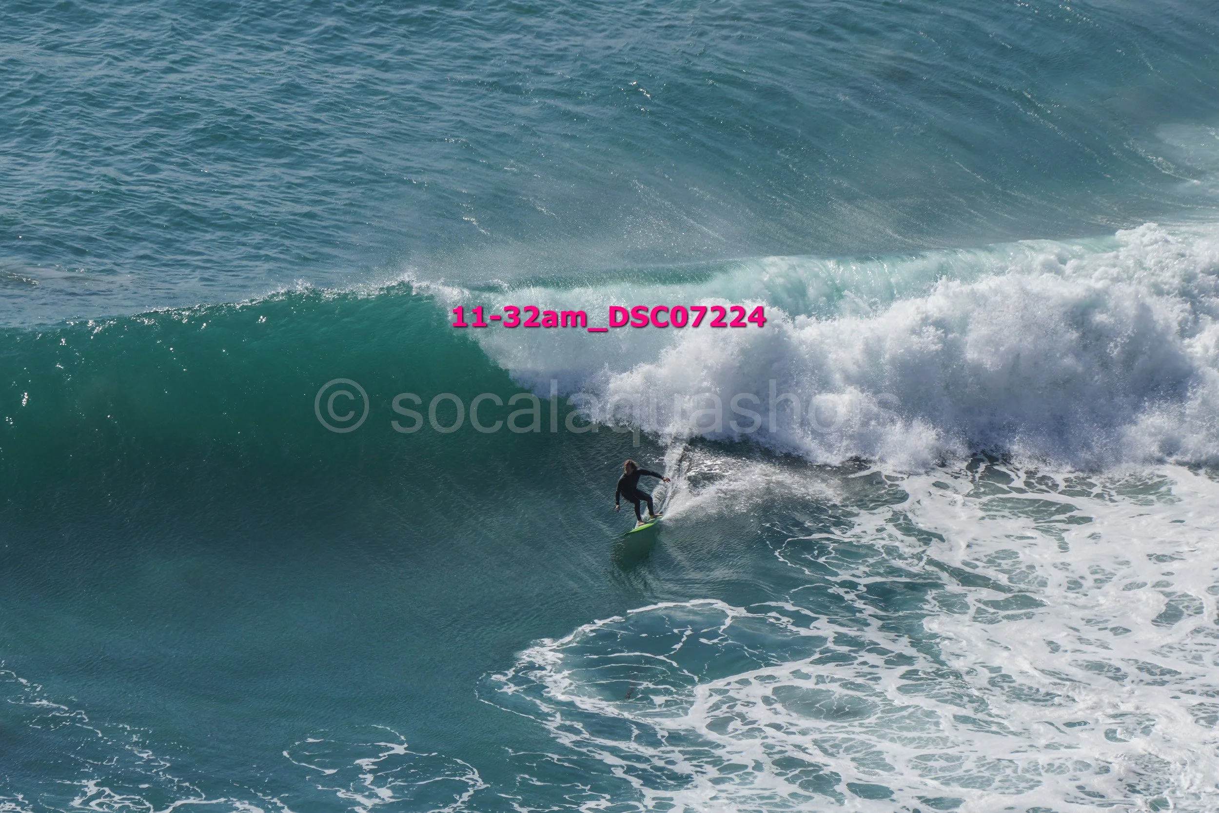 A surfer riding inside a large ocean wave with white foam and water spray.
