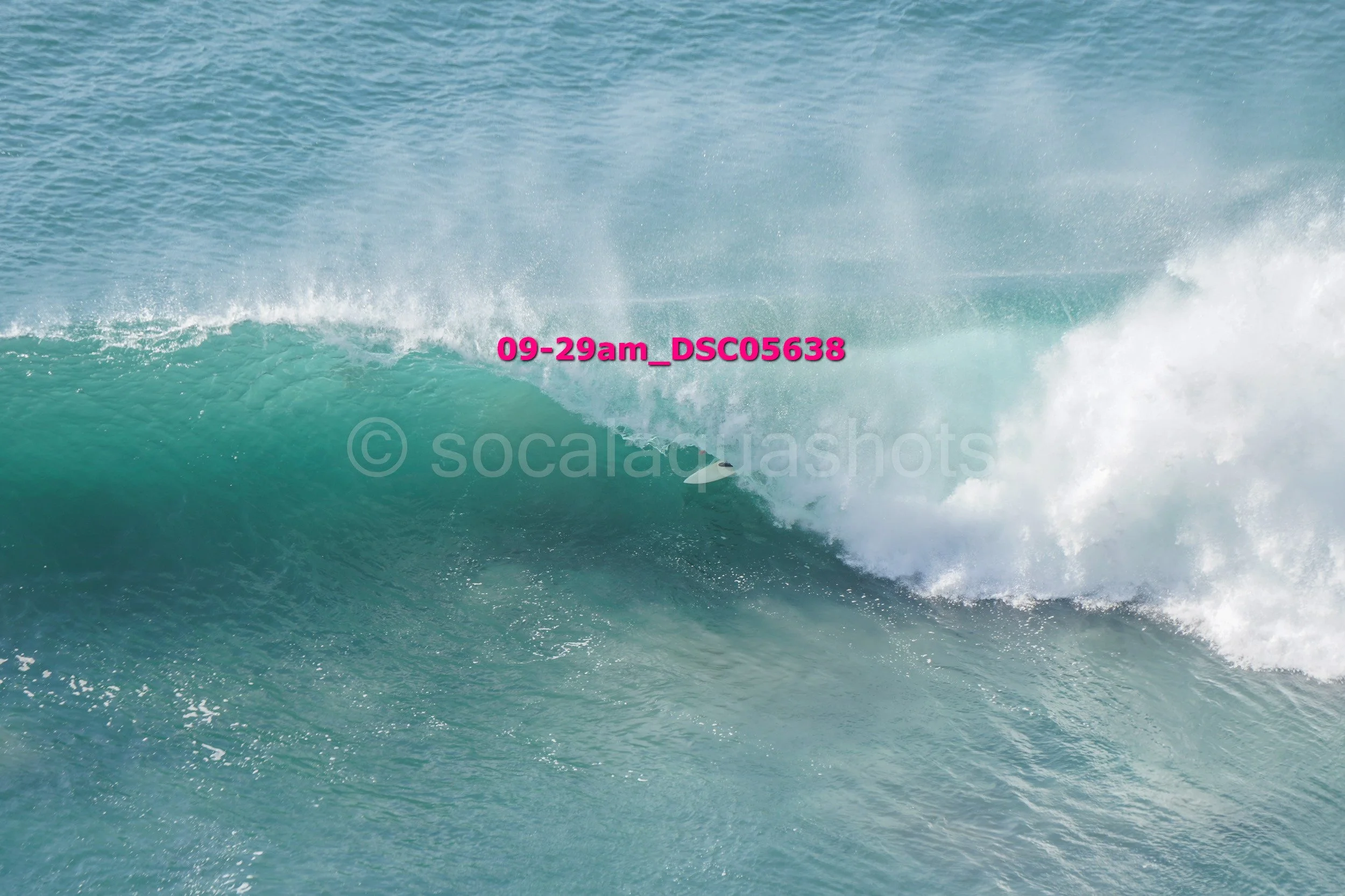 A surfer riding inside a large ocean wave with white foam at the crest.