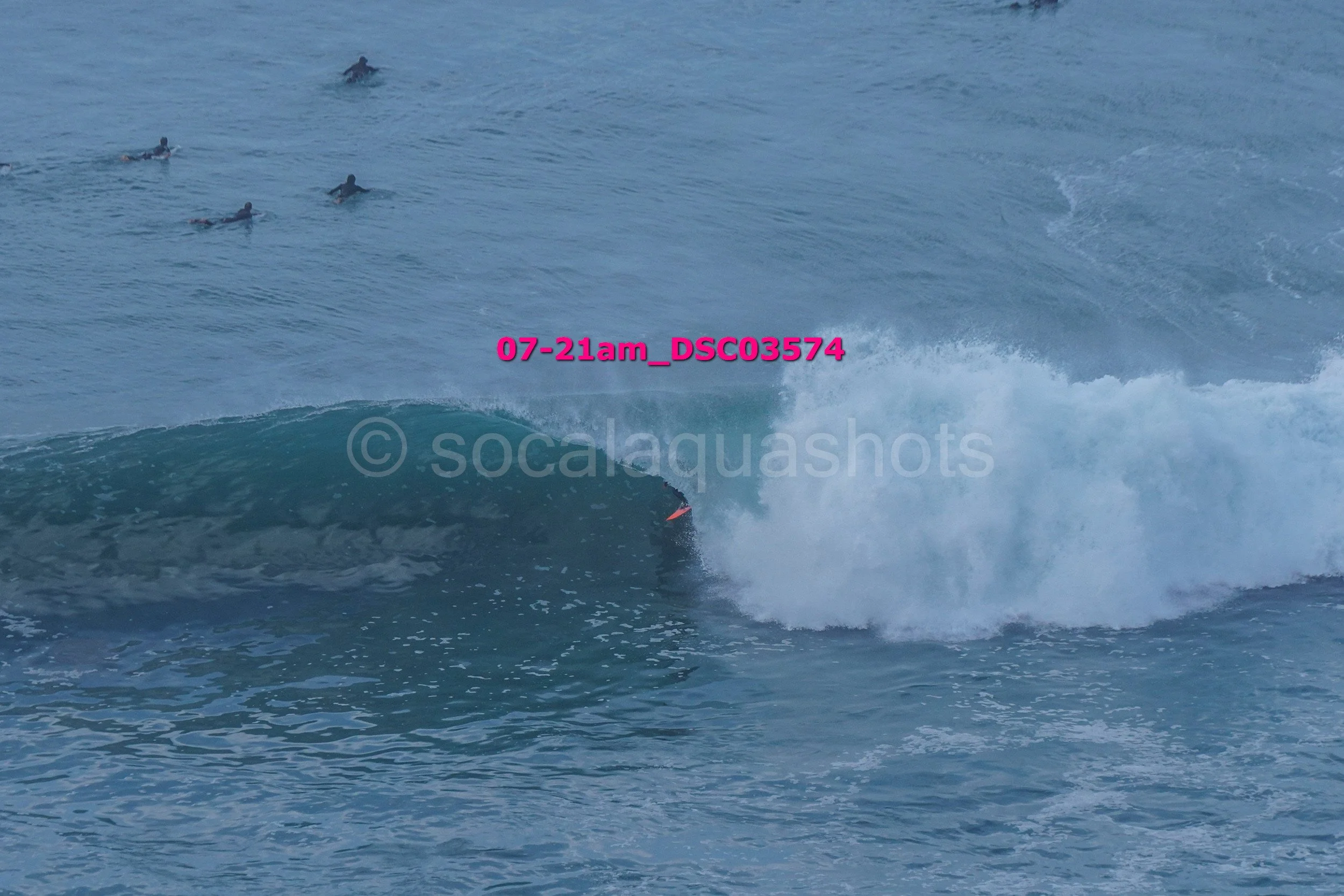 Surfer riding a wave with multiple surfers in the background in the ocean.