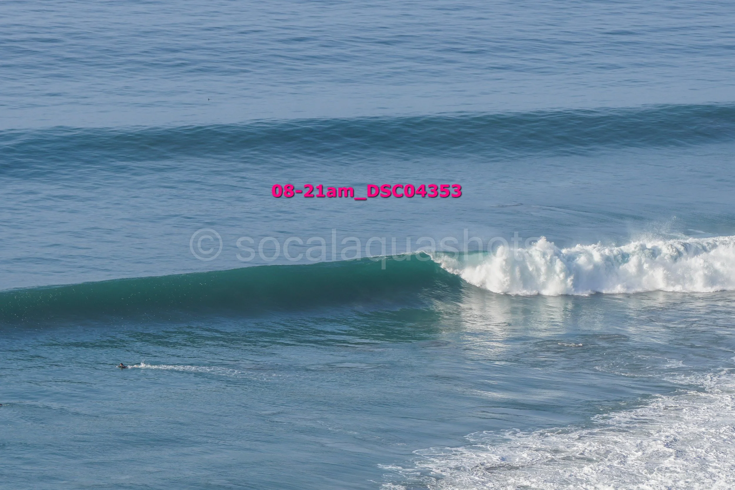 Ocean waves breaking near the shore under a clear sky.